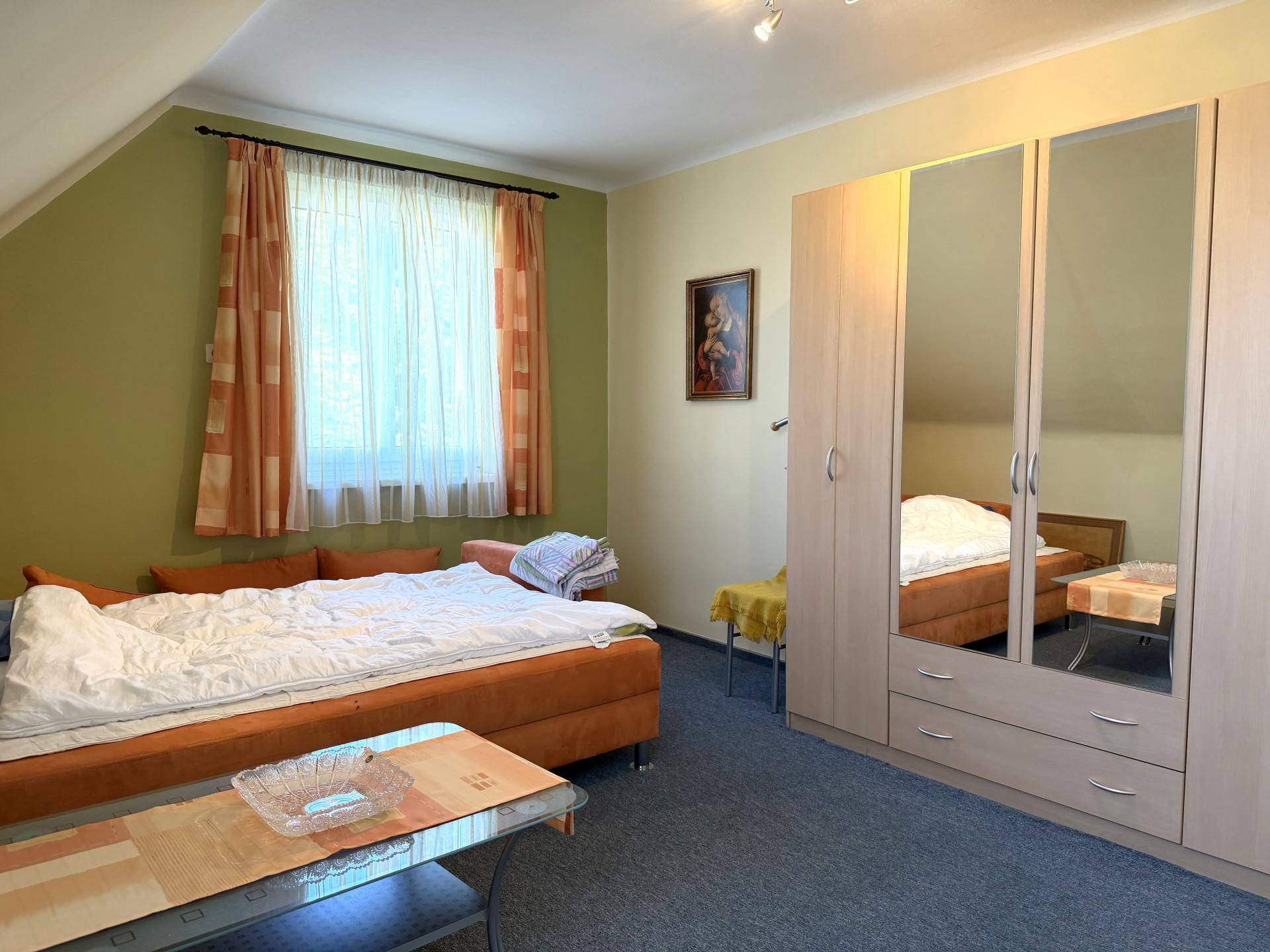 Helles Schlafzimmer mit Dachschräge, Teppichboden und Spiegelschrank.
