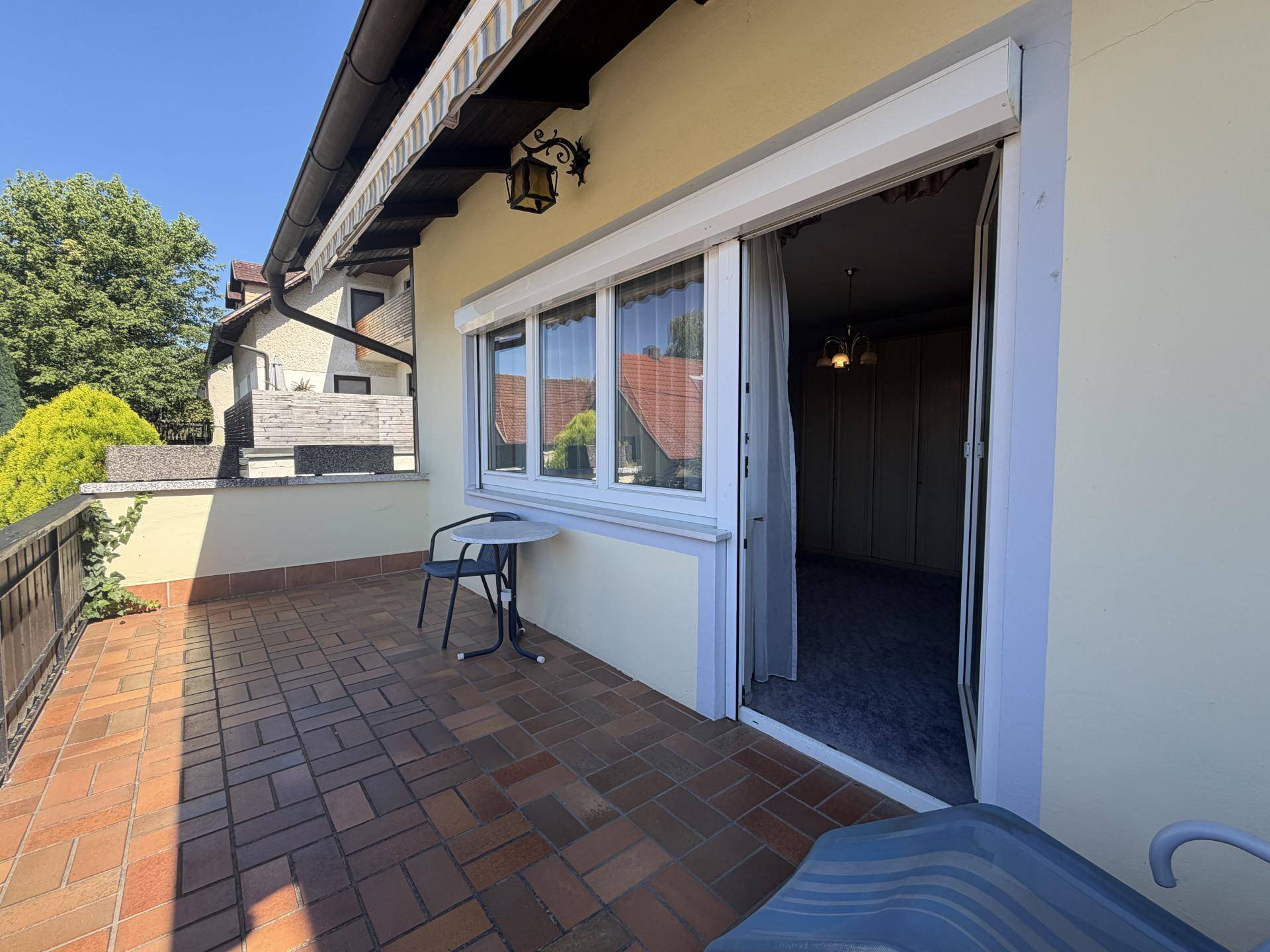 Gefliester Balkon mit Markise, Sitzgelegenheiten und Zugang zum Innenbereich.