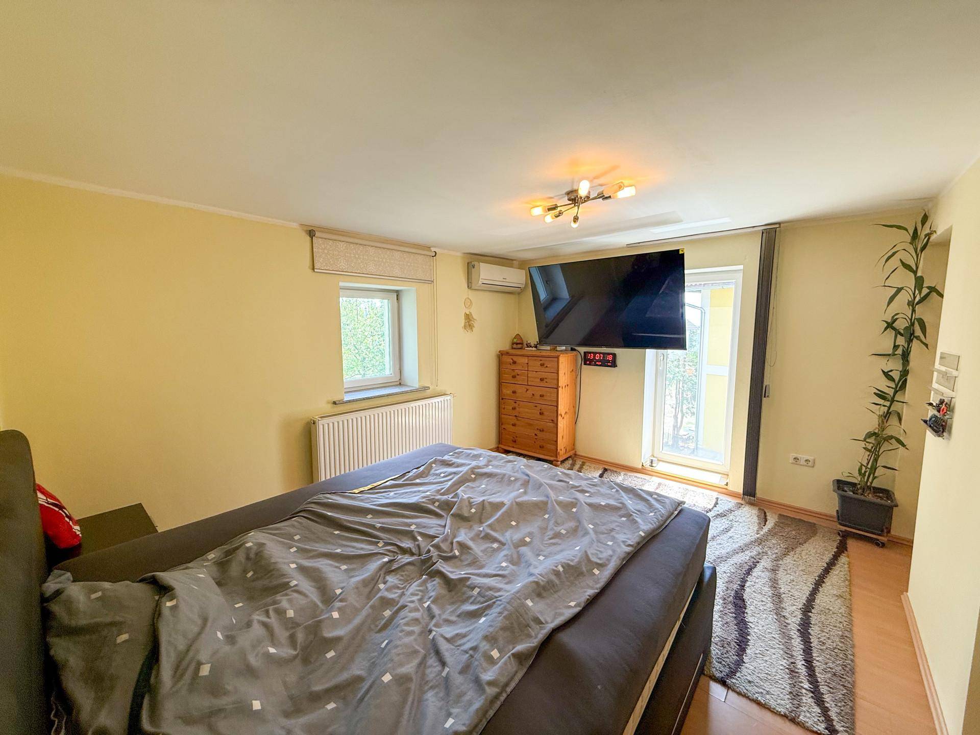 Schlafzimmer mit Doppelbett, Klimaanlage und Zugang zu einem Balkon oder einer Terrasse, hell und geräumig.