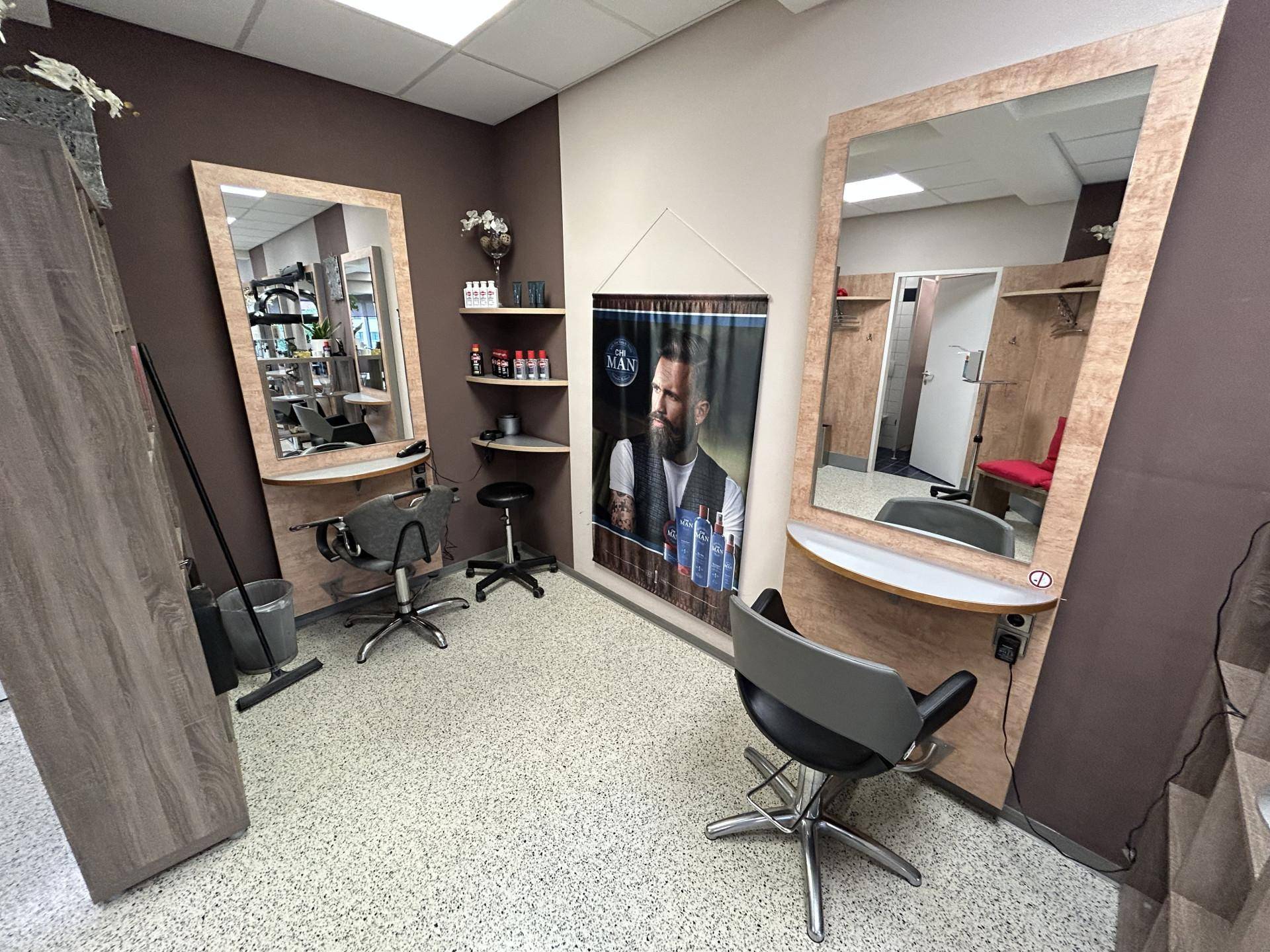 Bedienplätze im Friseursalon mit großen Spiegeln, Arbeitsstühlen und Produktregalen.