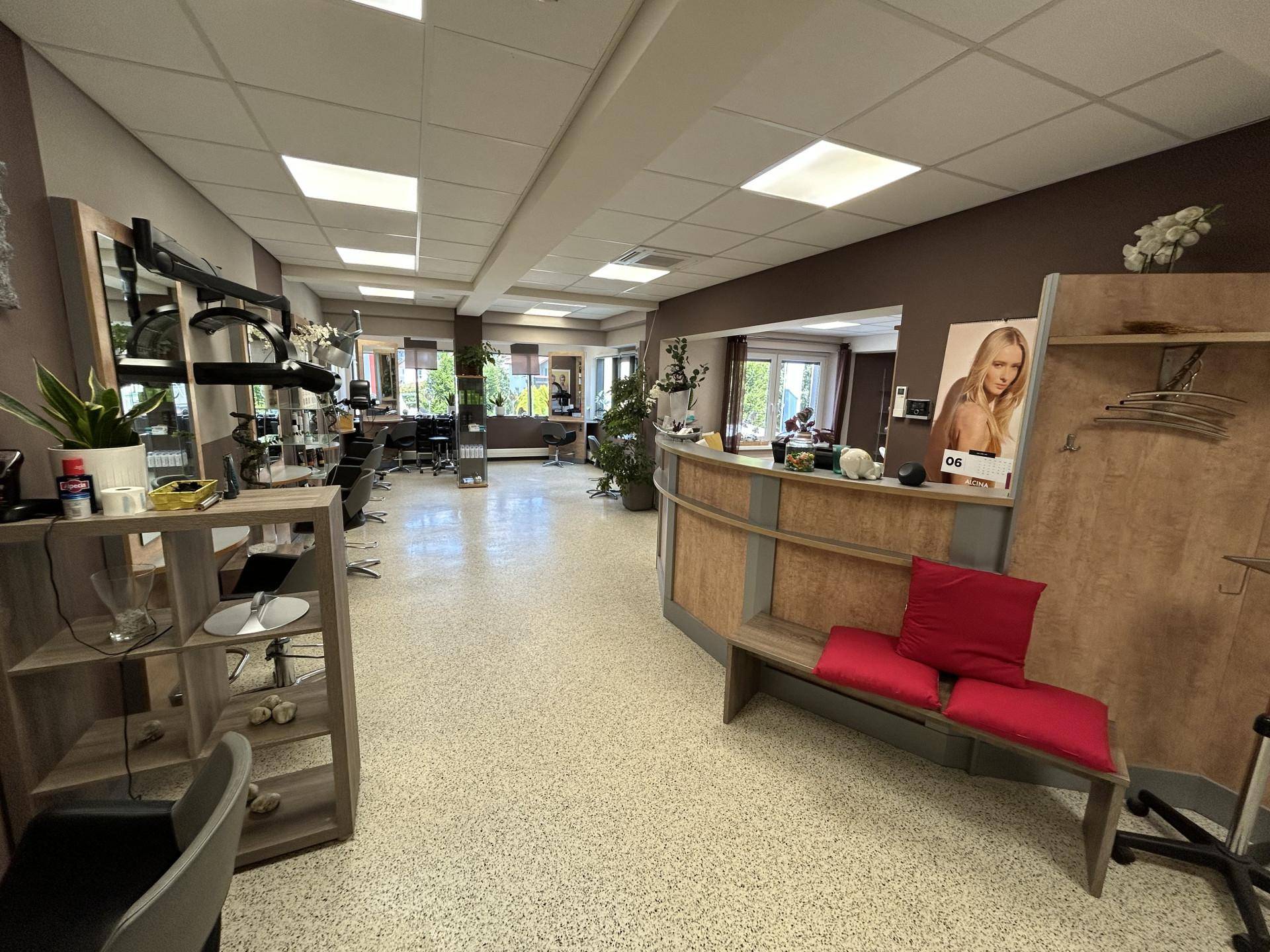 Blick durch den Friseursalon mit Rezeption, Wartebereich und weiteren Bedienplätzen.