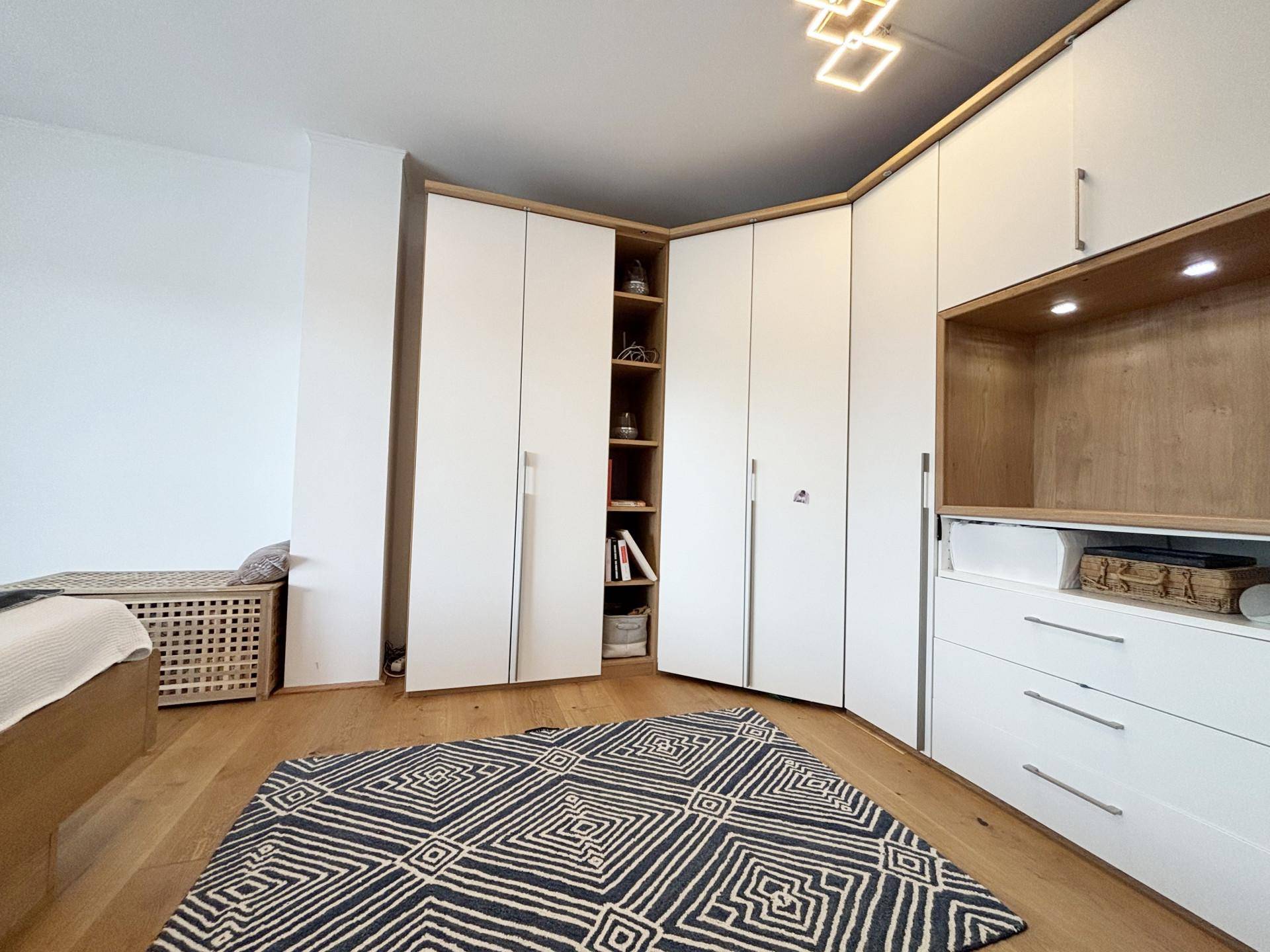 Schlafzimmer mit maßgefertigten Einbauschränken und hellem Holzfußboden.