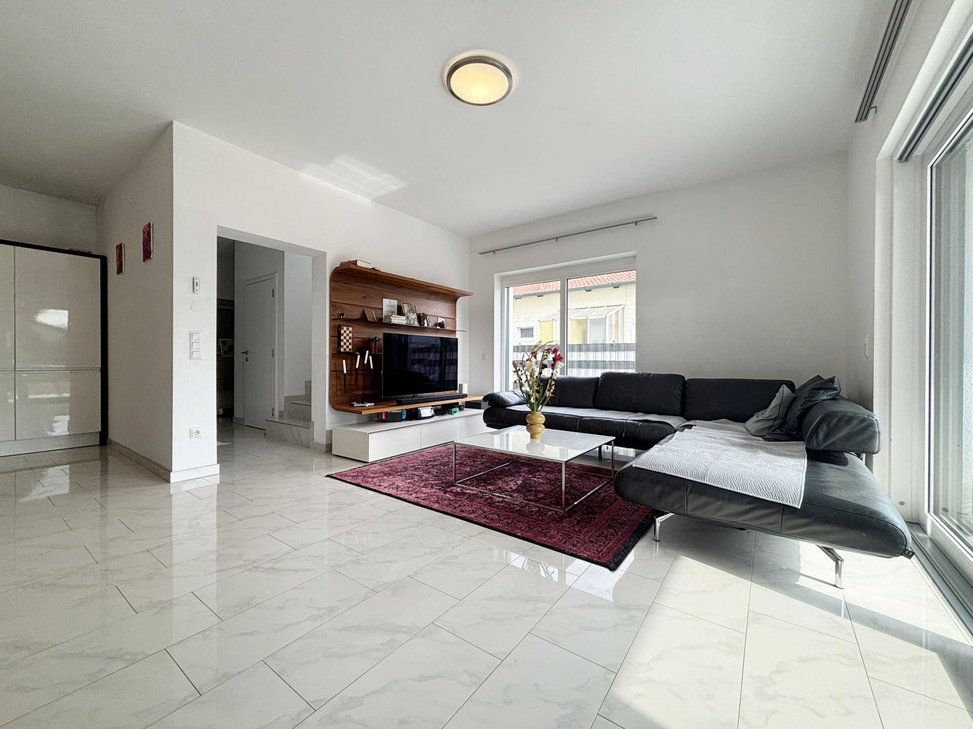 Helles Wohnzimmer mit modernem Sofa, TV-Möbel und glänzenden Fliesen.