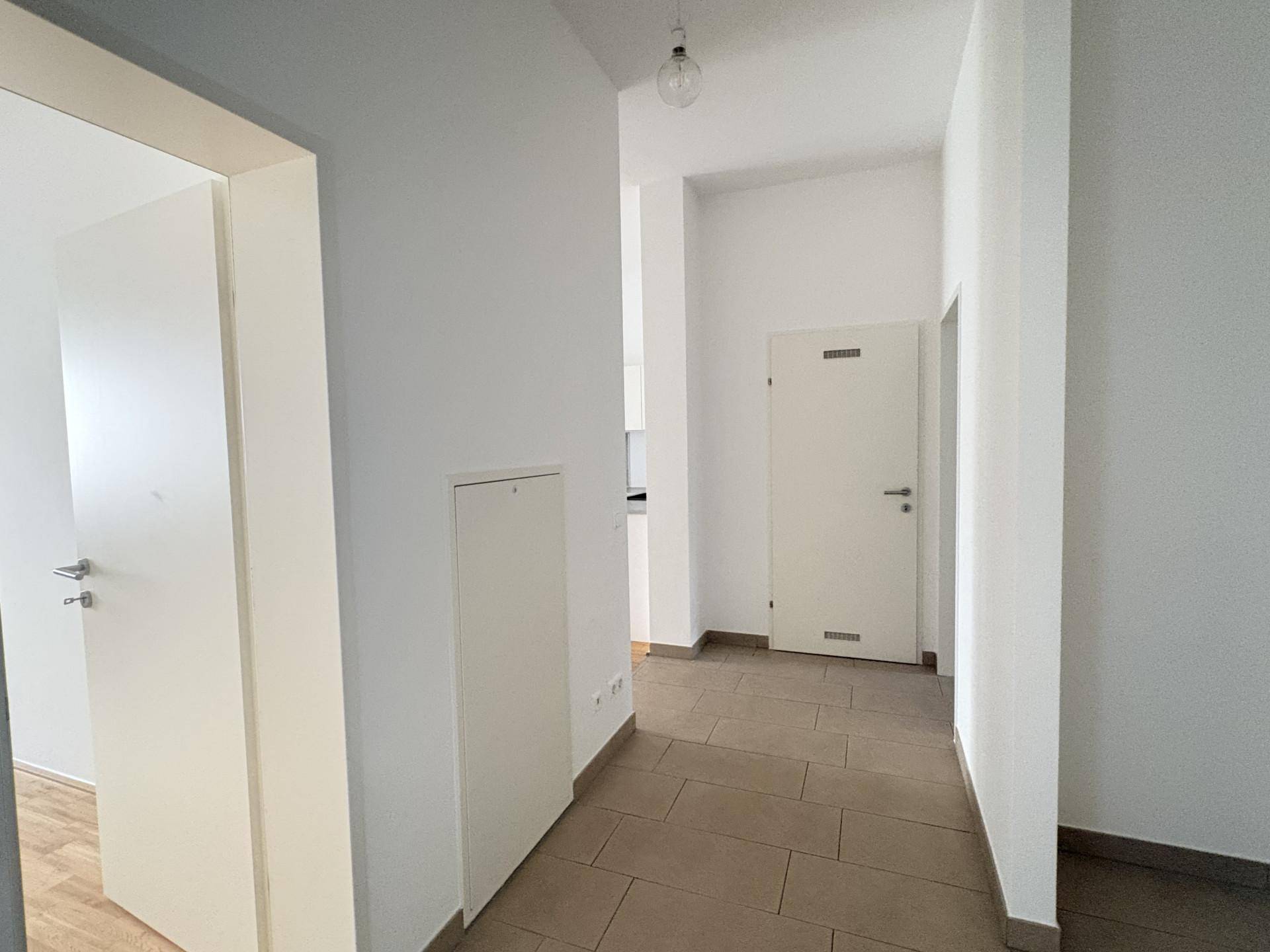 Heller Flur mit Fliesenboden und mehreren Türen, die zu den angrenzenden Räumen führen.