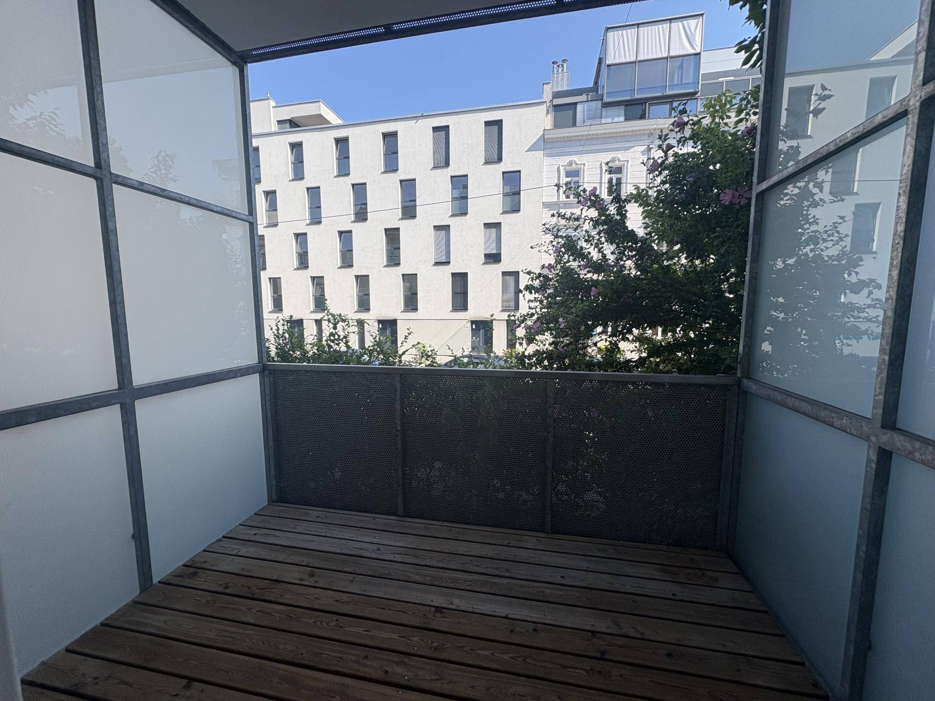 Balkon mit Holzfußboden und Blick auf die umliegenden Gebäude in der Stadt.