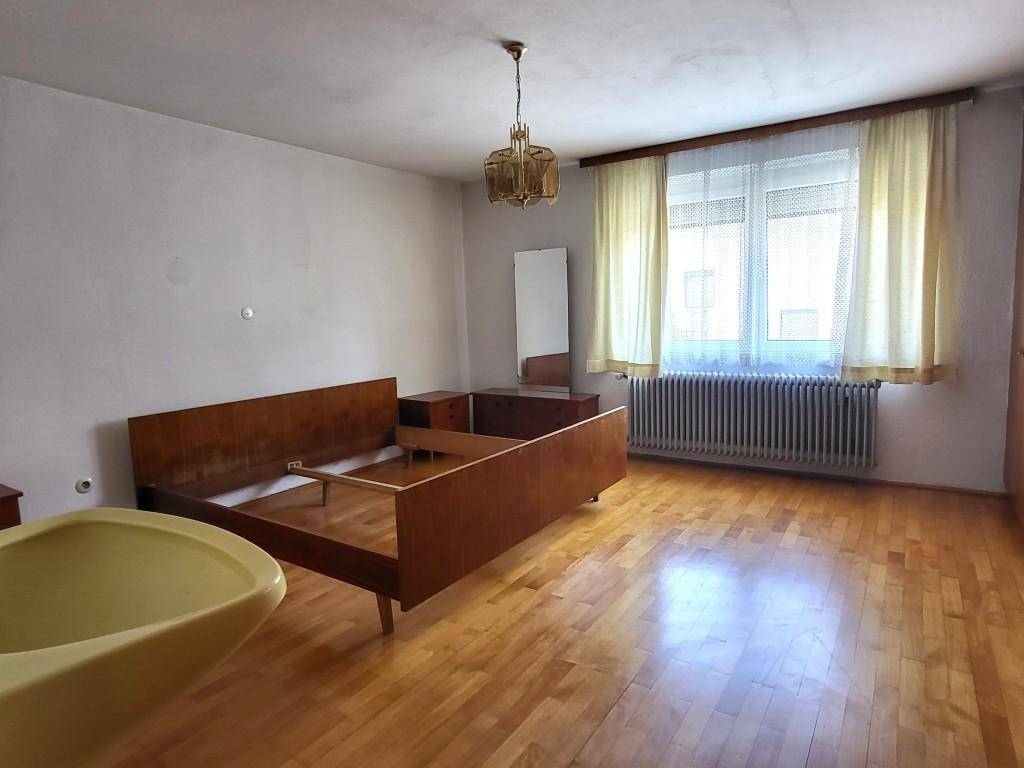 Geräumiges Schlafzimmer mit Holzboden, großem Fenster und Vintage-Möbeln, hell und einladend.