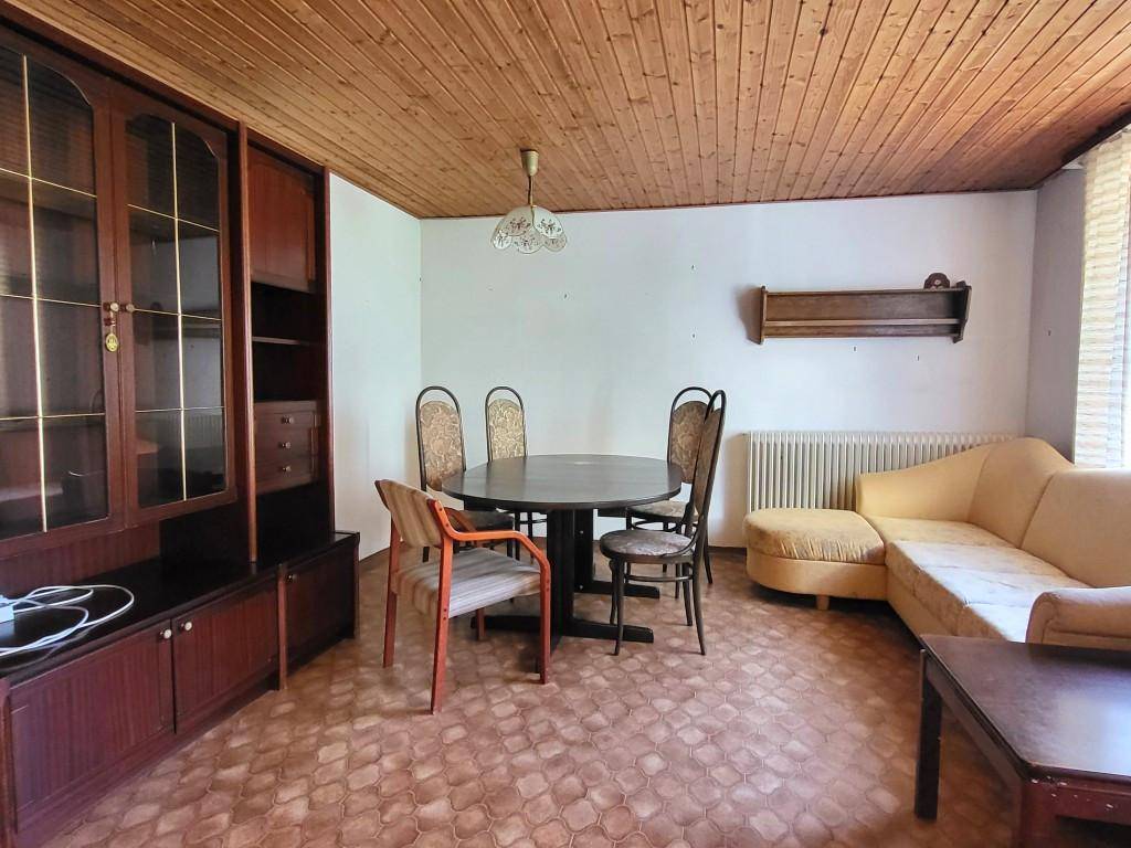 Wohn- und Essbereich mit Holztäfelung an der Decke und traditionellen Möbeln, gemütlich eingerichtet.