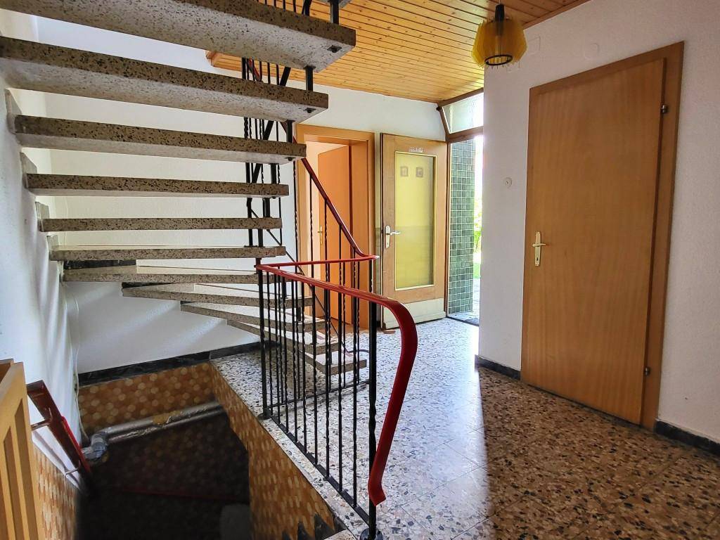 Heller Flur mit Terrazzoboden und Treppe ins Obergeschoss, typisch für Altbau.