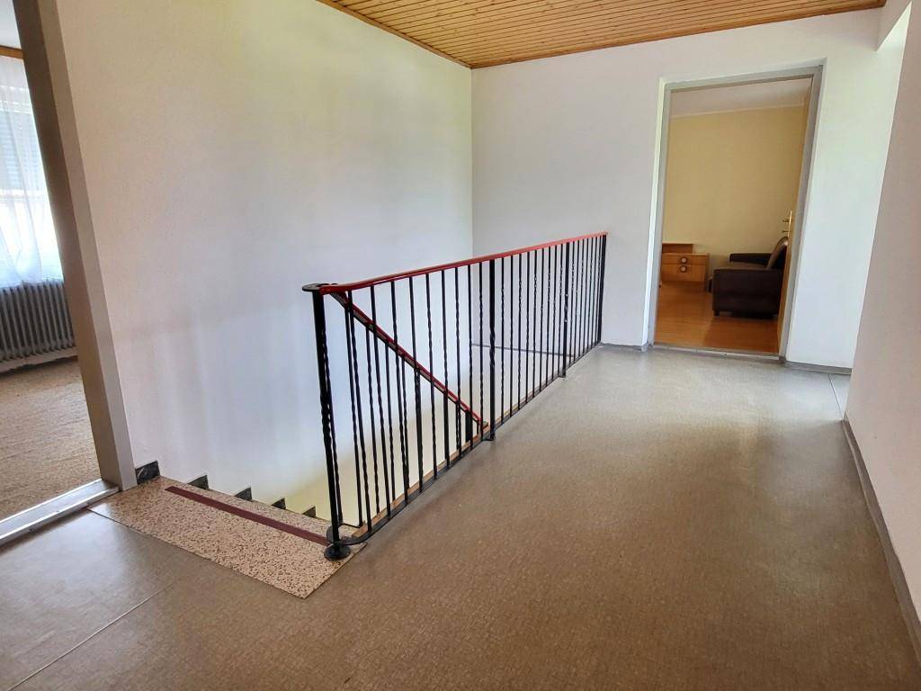 Heller Flur im Obergeschoss mit Holzdecke und Blick auf die Treppe, gut erhalten.