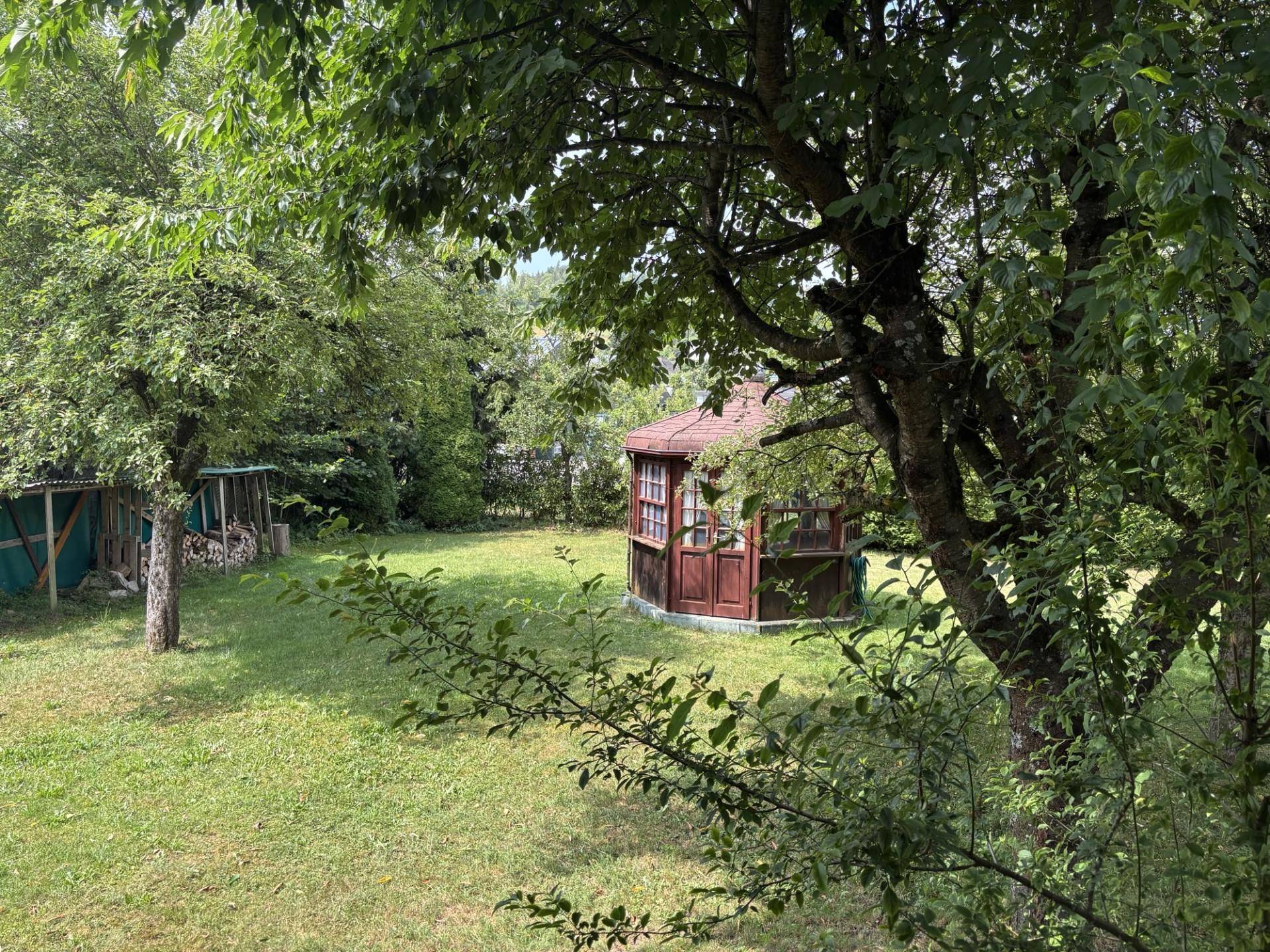 Idyllischer Garten mit einem hölzernen Pavillon und altem Baumbestand.