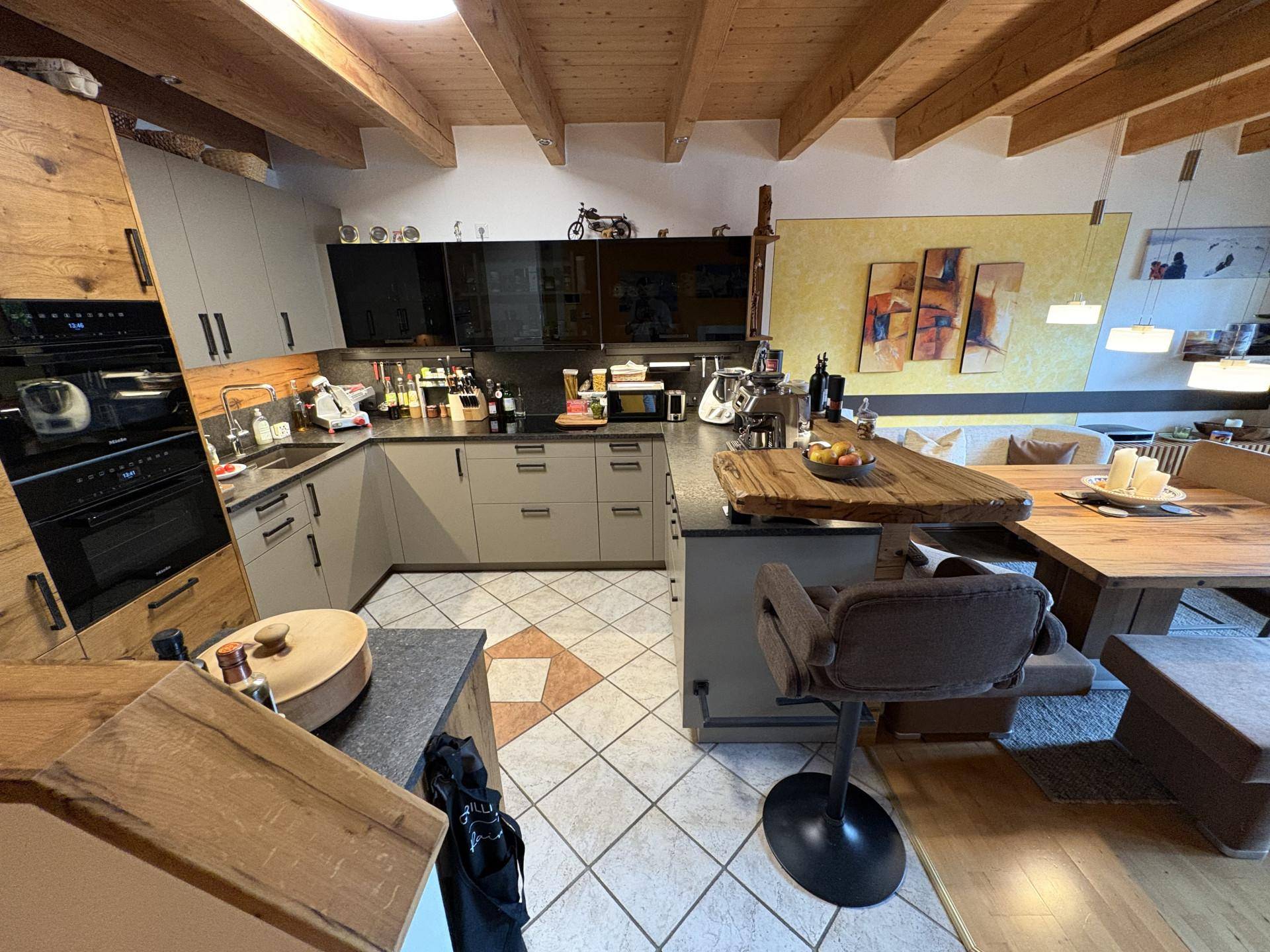 Moderne Küche mit grauen und schwarzen Schränken, integrierten Geräten und einer Kücheninsel mit Bar.