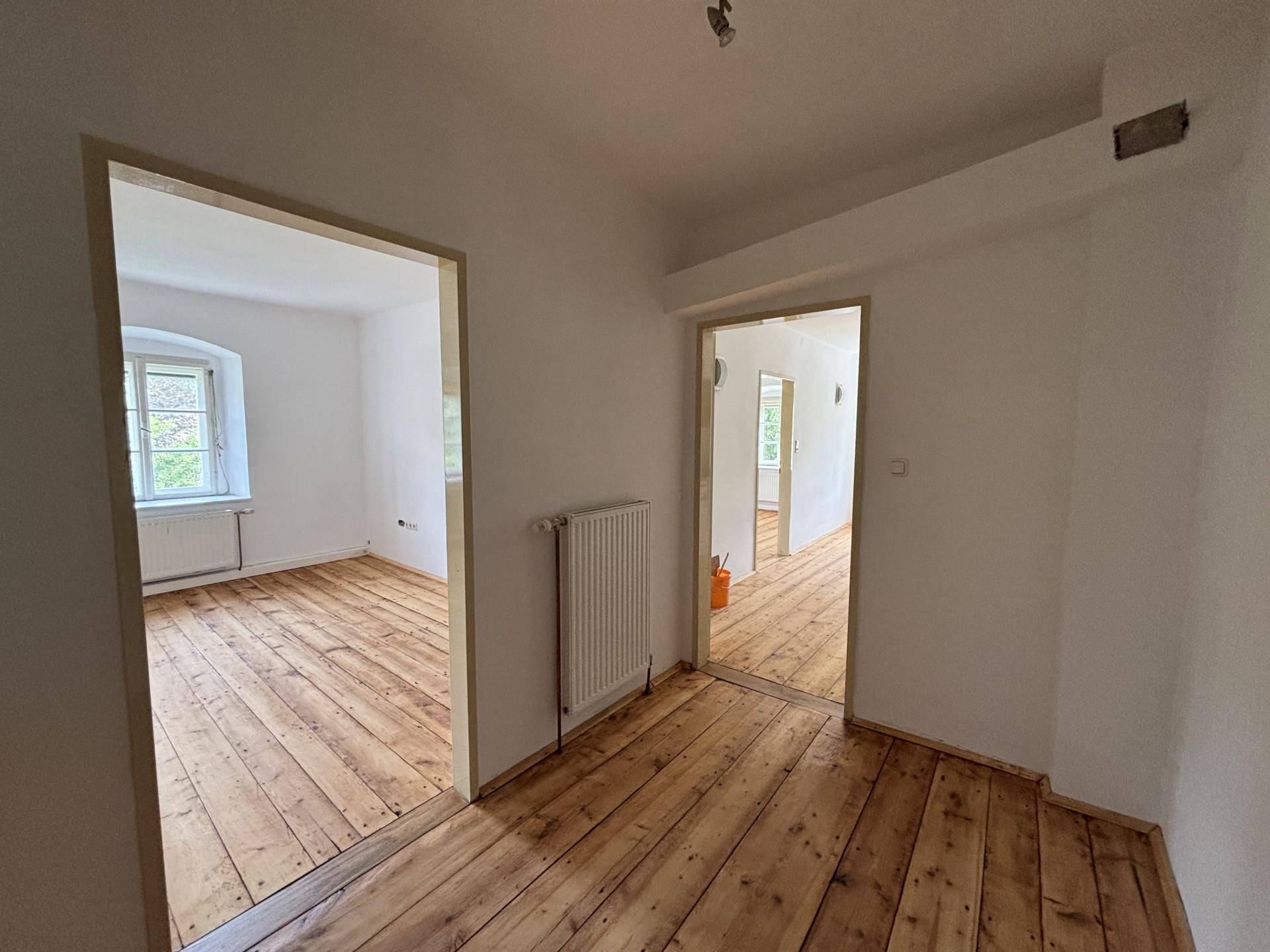 Heller Flur mit Holzdielenboden, der zu weiteren Zimmern mit ähnlicher Ausstattung führt.