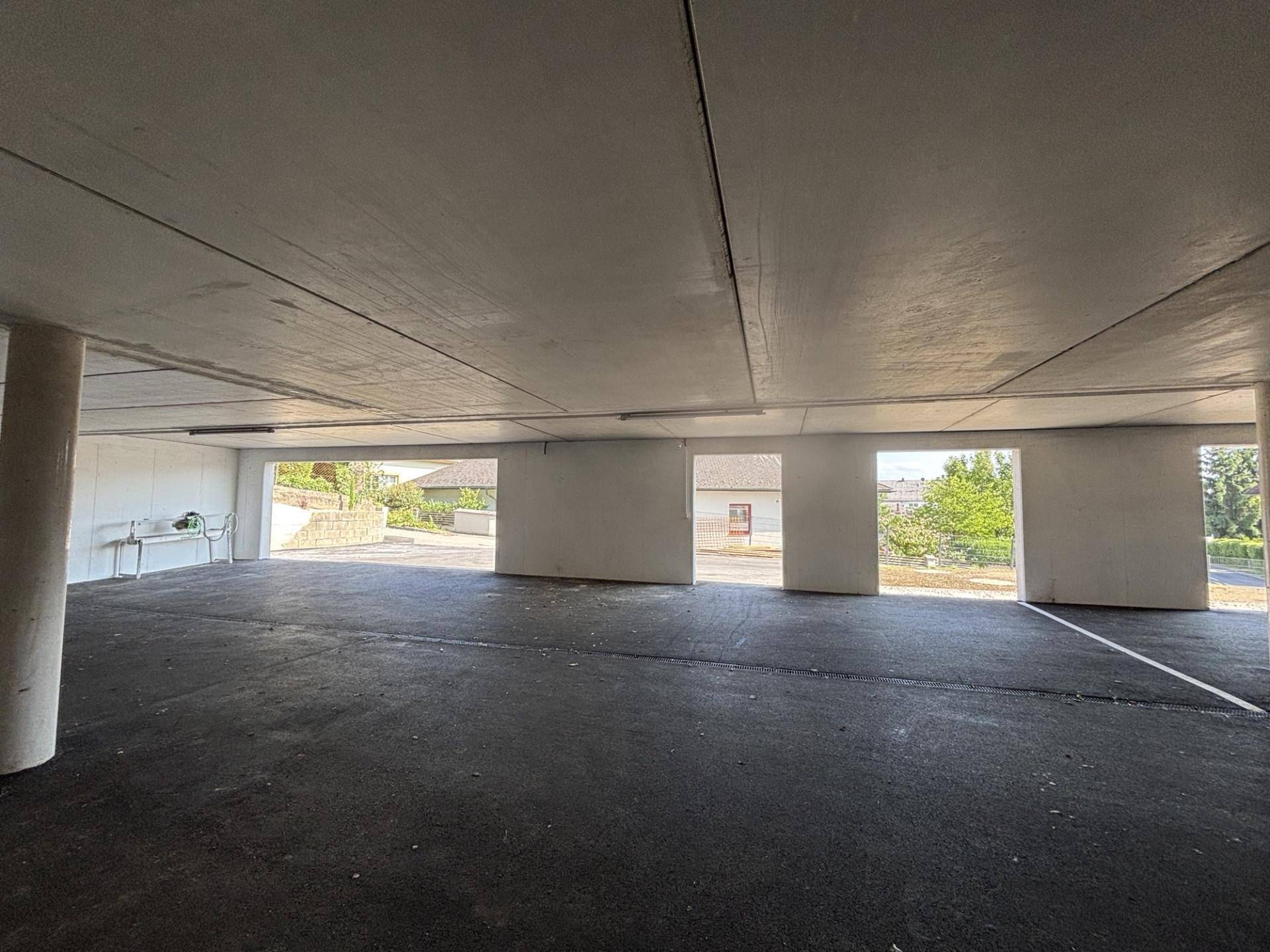 Geräumige Tiefgarage mit Betonboden und mehreren Ausfahrten ins Freie.