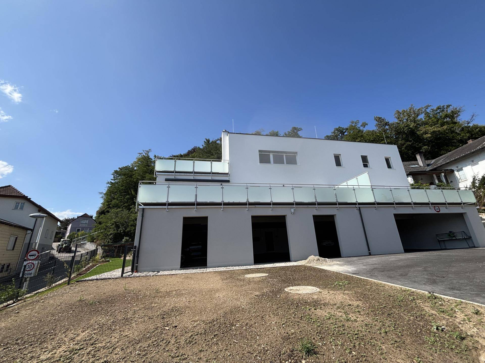 Moderne Architektur mit weißer Fassade und Glasbalkonen, umgeben von Grünflächen.