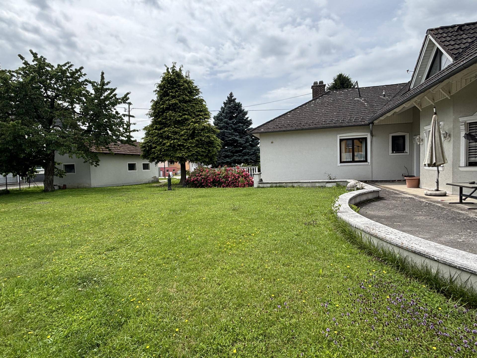 Weitläufiger Gartenbereich mit Rasenfläche und verschiedenen Bäumen neben dem Haus.