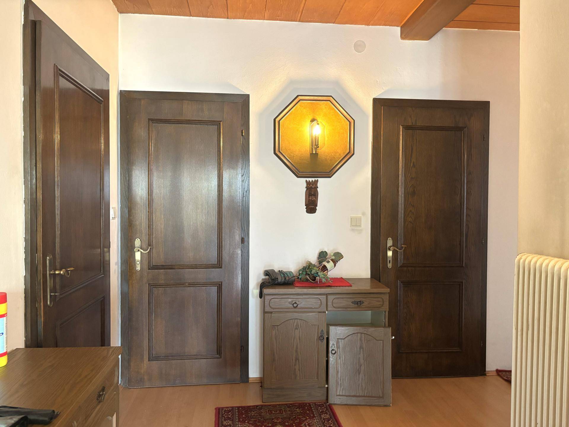 Traditioneller Flur mit Holztüren, Holzdecke und einem antiken Wandleuchter.