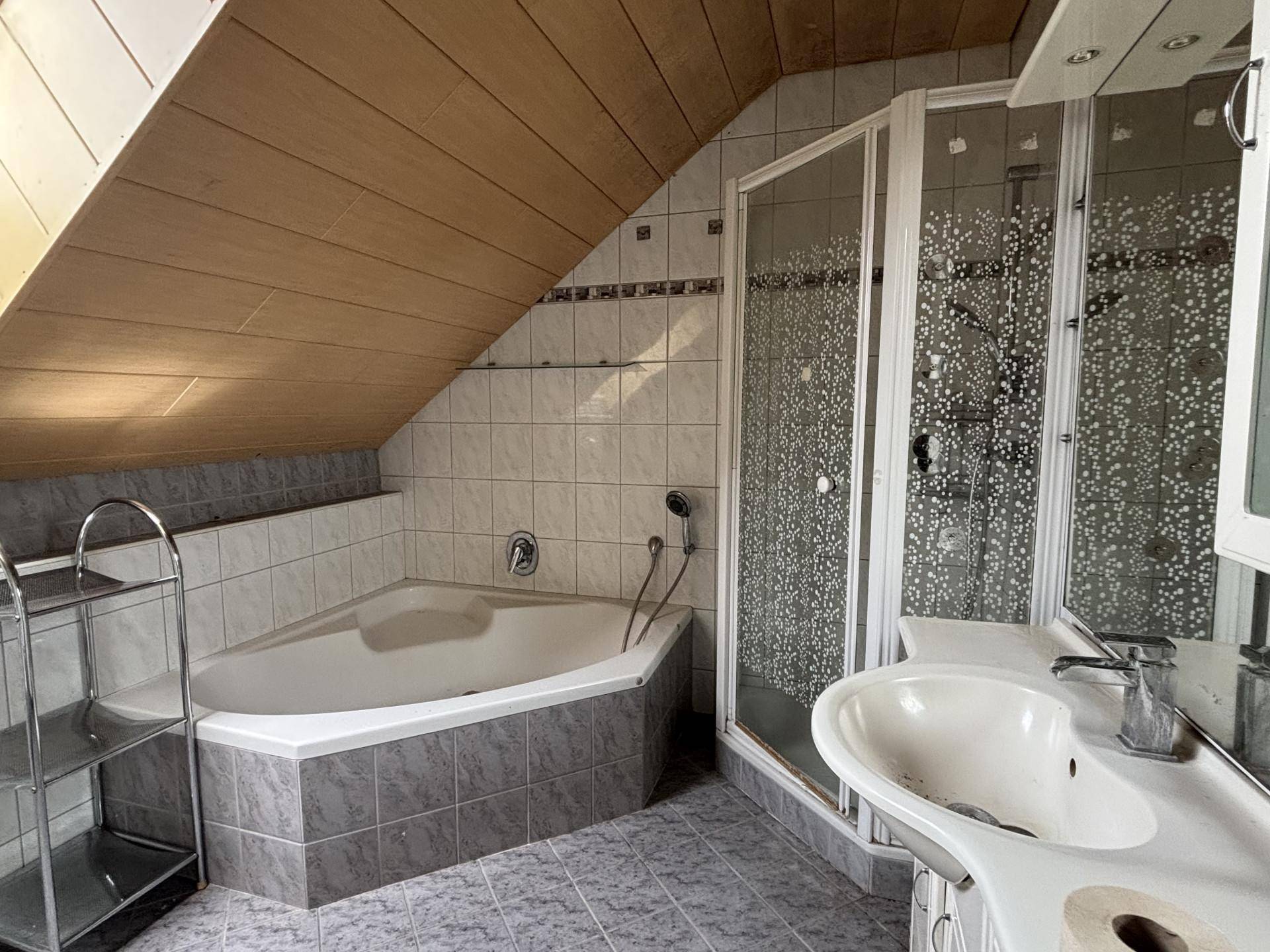 Geräumiges Dachgeschoss-Badezimmer mit Eckbadewanne, Duschkabine und Waschtisch.