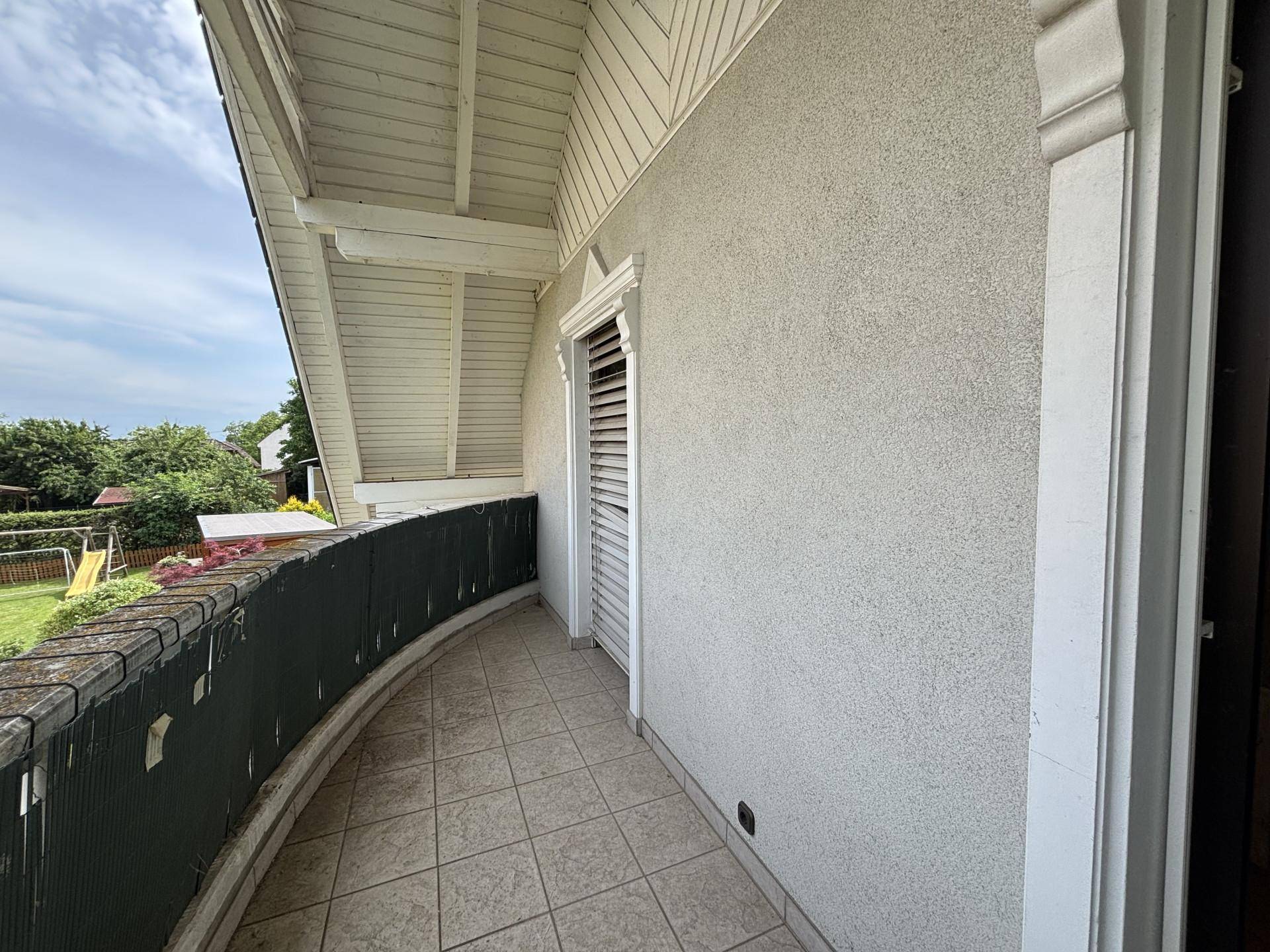 Langer Balkon mit Fliesenboden und Blick ins Grüne.