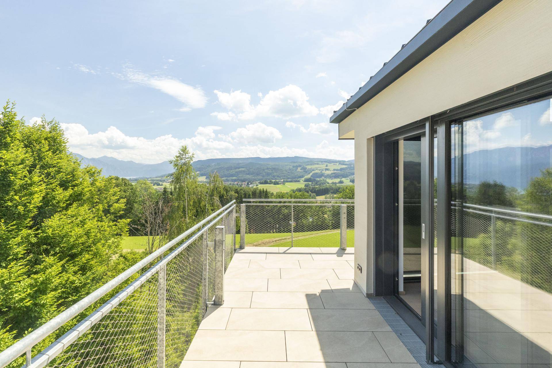 Heller Balkon mit modernen Schiebetüren und weitem Panoramablick über die hügelige Landschaft.