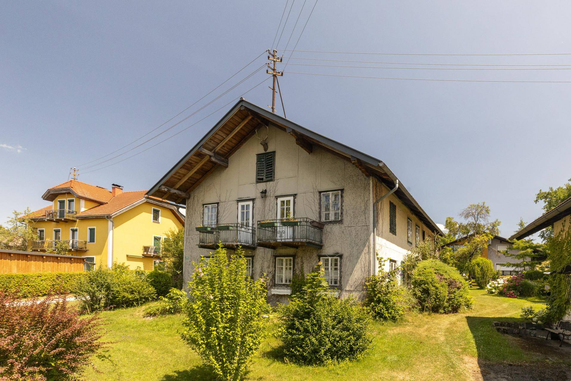 Altes Wohnhaus mit mehreren Balkonen und einem weitläufigen Gartenbereich mit Seeblick.