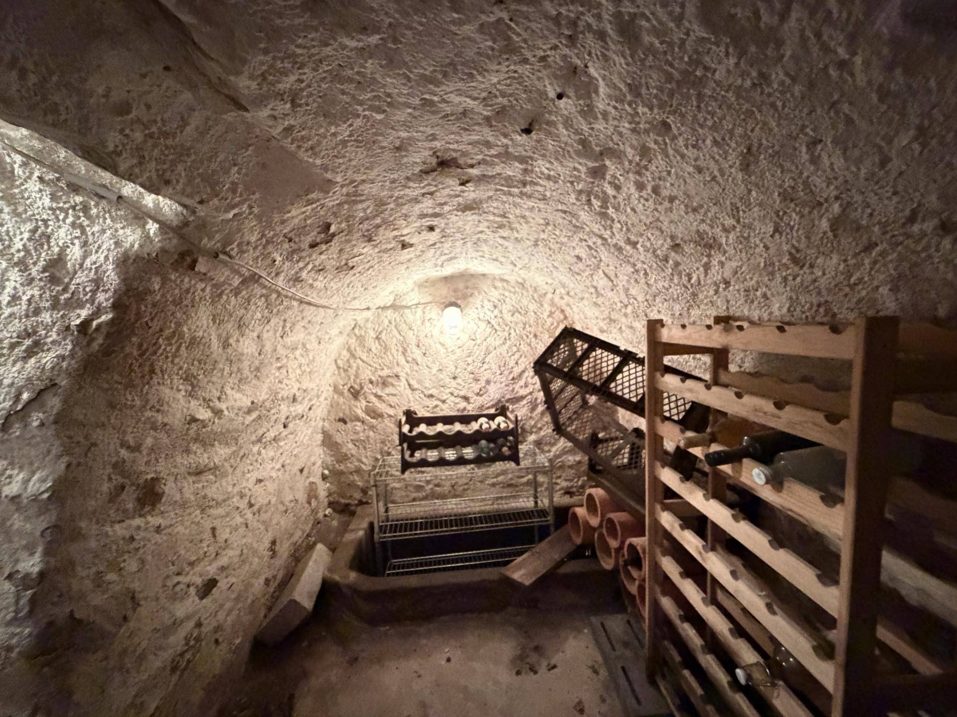 Historischer Kellerraum mit Gewölbedecke und Holzregalen für Weinflaschen.