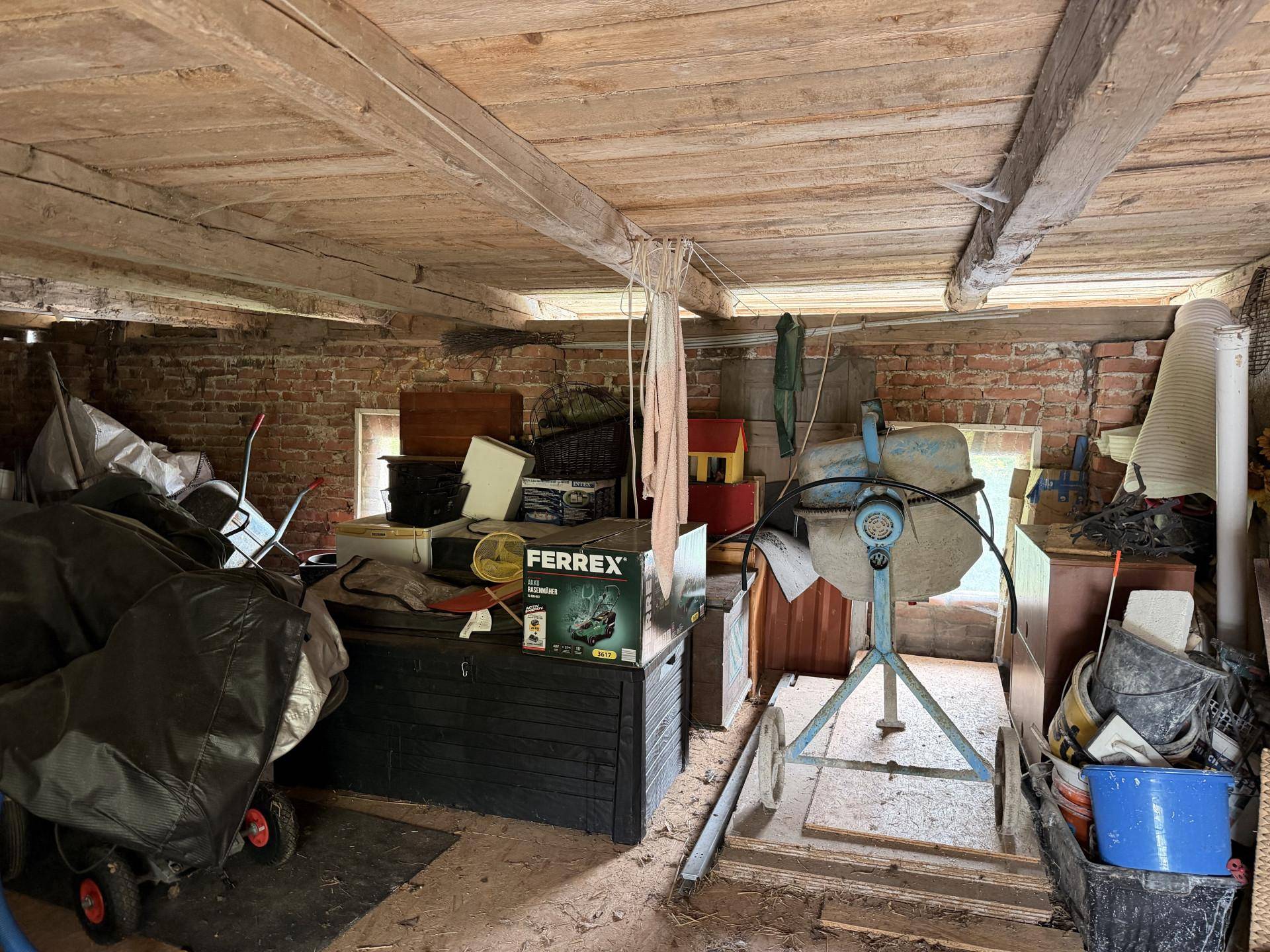 Werkstattraum mit Ziegelwänden, Holzbalkendecke und verschiedenen Arbeitsgeräten.