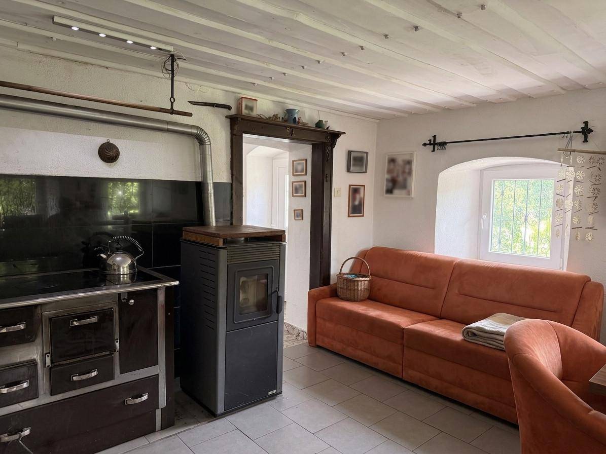 Gemütliches Wohnzimmer mit Kaminofen, Holzbalkendecke und bequemer Couch.