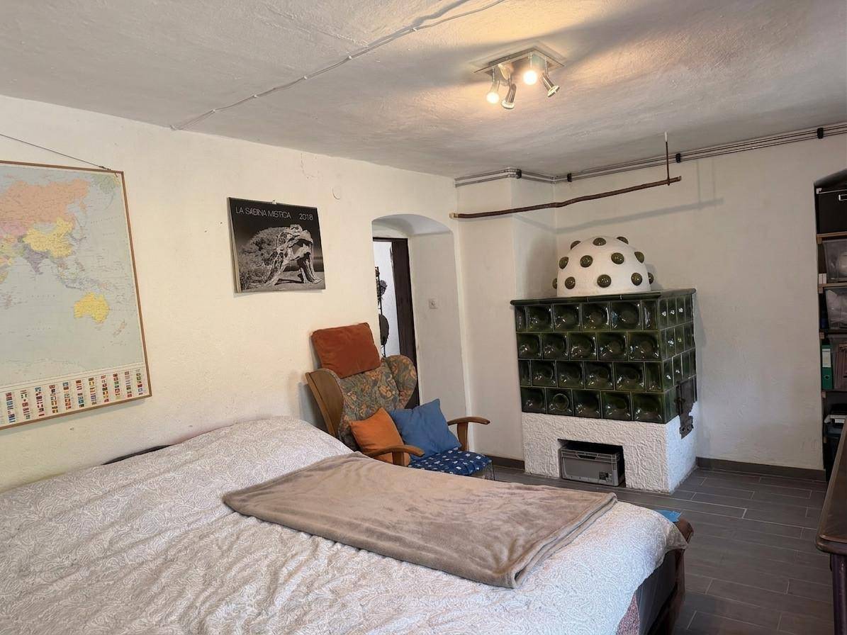 Schlafzimmer mit Kachelofen, Doppelbett und Weltkarte an der Wand.