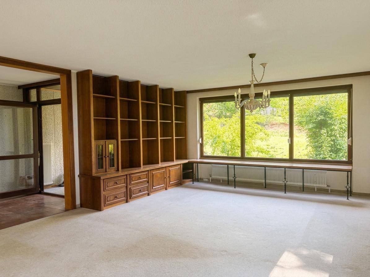 Geräumiges Wohnzimmer mit großem Einbauregal aus Holz und weitem Blick ins Grüne.