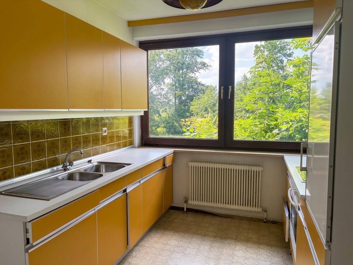 Küche im Vintage-Stil mit gelben Schränken, Fliesenrückwand und Blick ins Grüne.