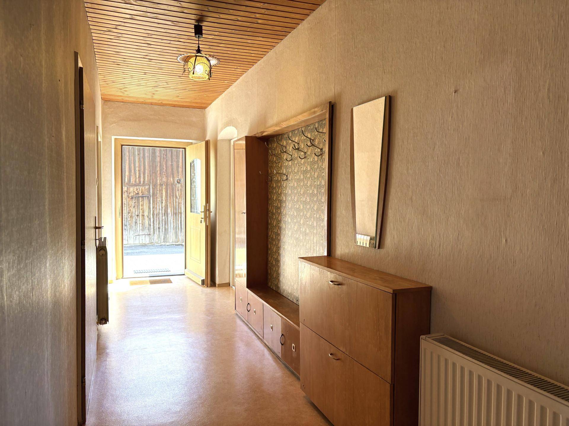 Heller Flur mit Holzdecke, Garderobe und Schuhschrank, der zum Eingangsbereich führt.