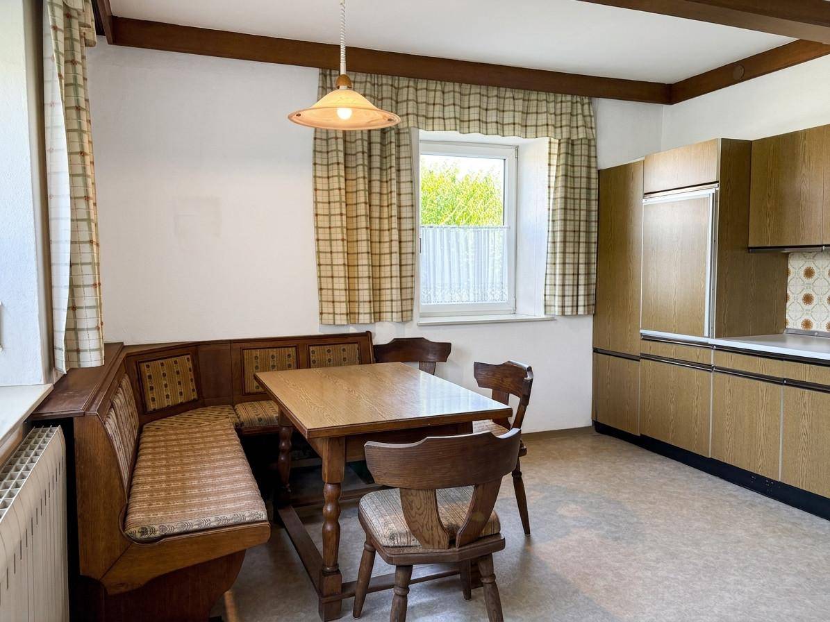 Gemütliche Wohnküche im Landhausstil mit Holzbalken, Eckbank und traditionellen Möbeln.