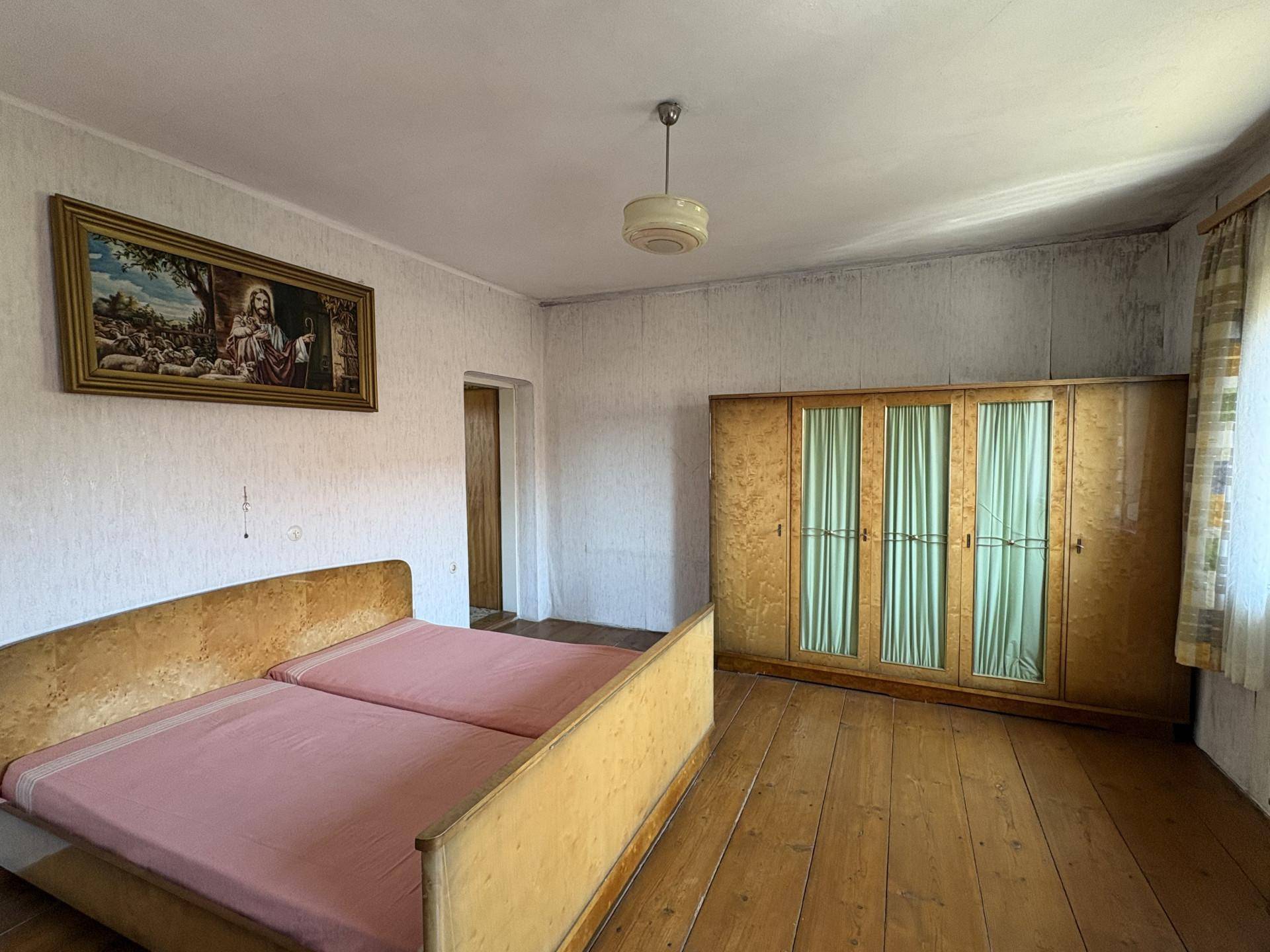 Schlafzimmer mit Holzdielenboden, Doppelbett und einem großen Kleiderschrank im Vintage-Stil.