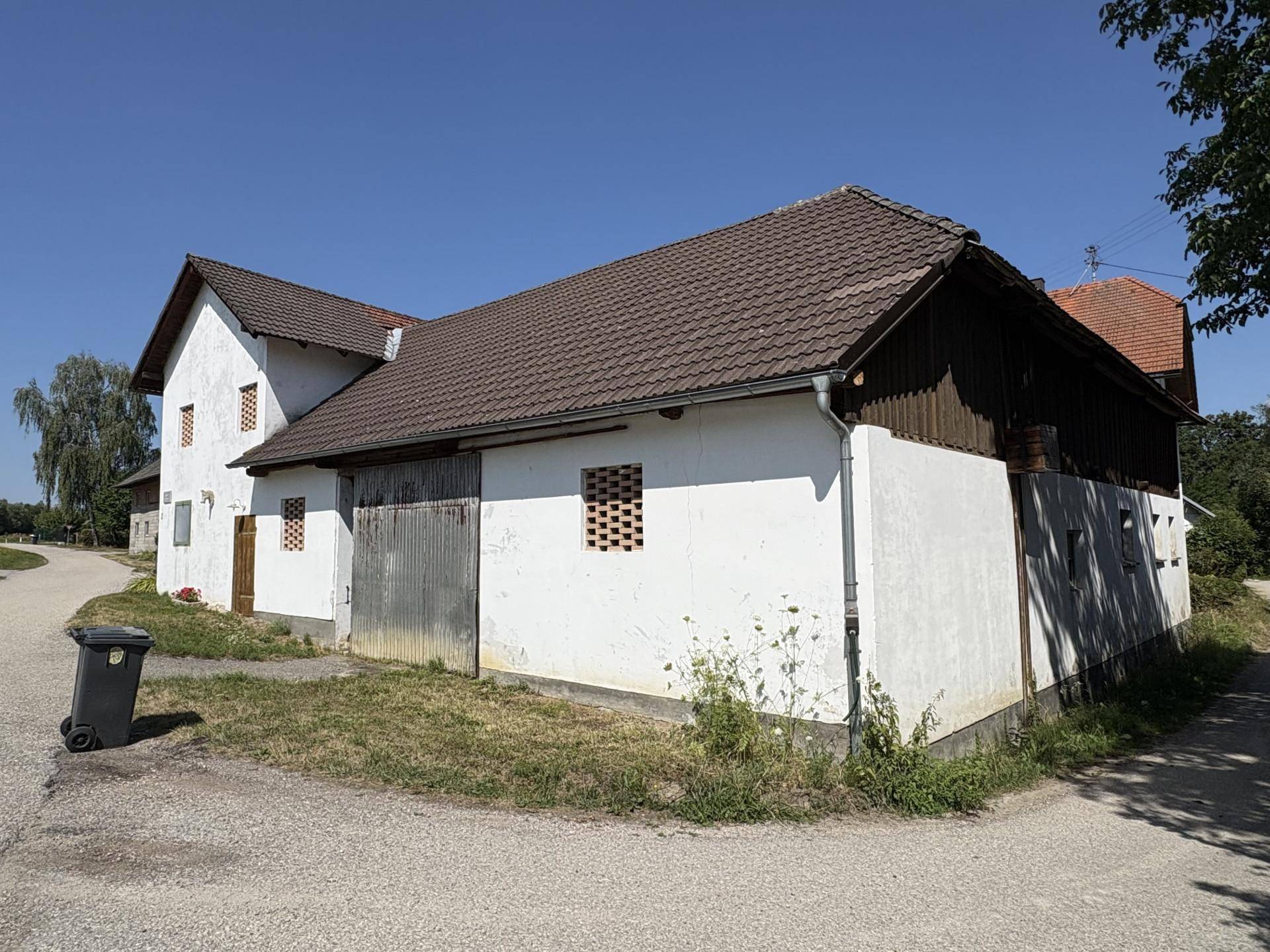 Seitenansicht des Bauernhofs mit weiß getünchten Wänden und traditionellem Holzanbau.