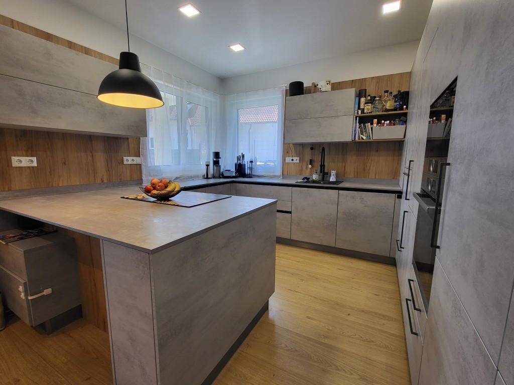 Moderne Küche mit grauen Fronten, Holzakzenten und einer Kücheninsel.