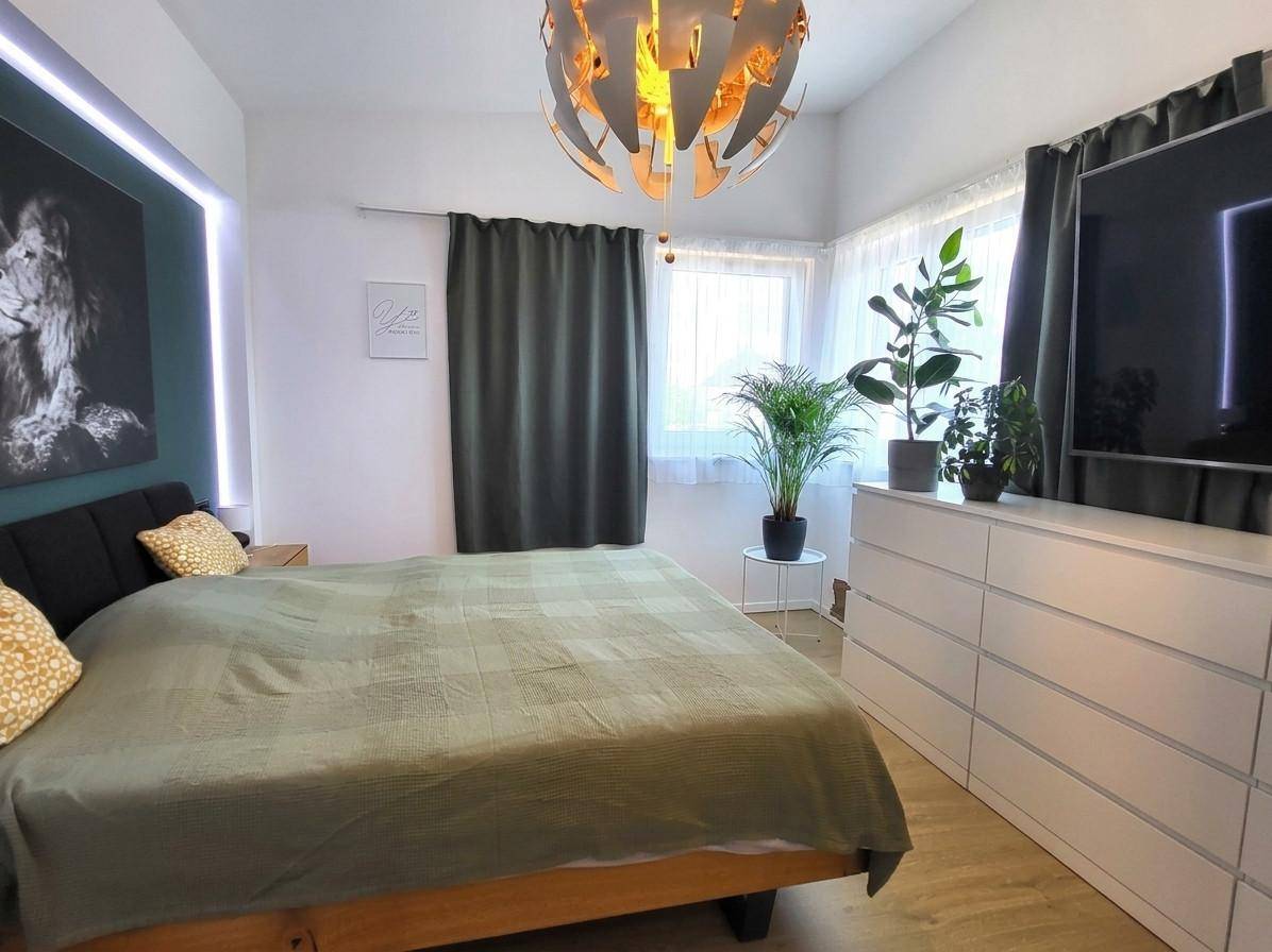 Schlafzimmer mit Doppelbett, grüner Bettwäsche und dekorativer Beleuchtung.