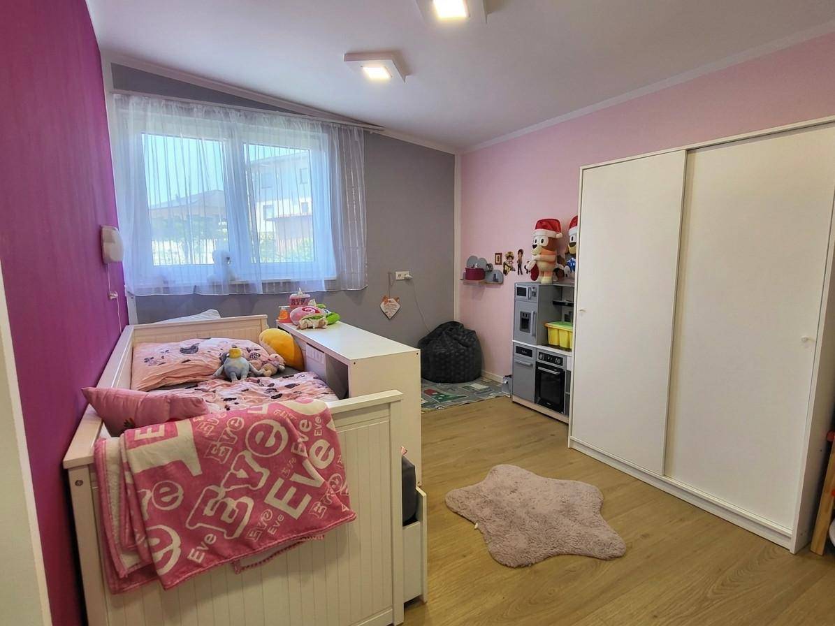 Kinderzimmer mit Babybett, Spielzeug und rosa Wandakzenten.