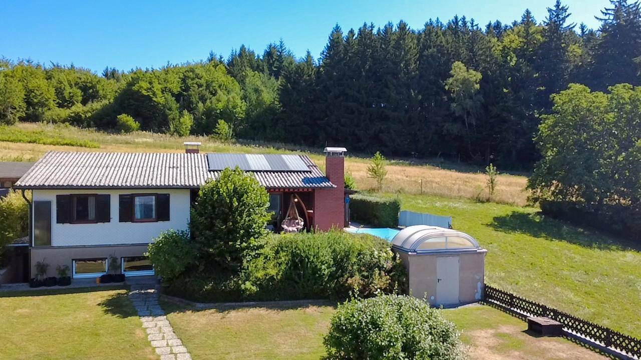 Freistehendes Haus mit großem Garten, Pool und Photovoltaikanlage auf dem Dach.