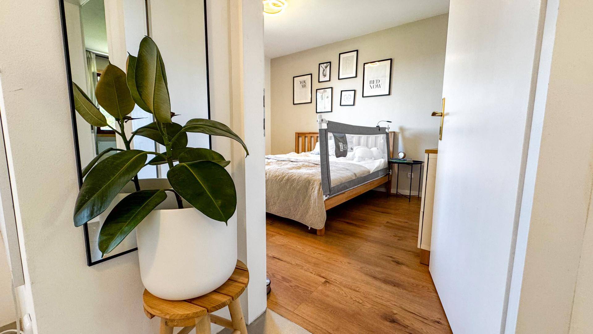 Gemütliches Schlafzimmer mit Holzbett, Holzboden und minimalistischer Wanddekoration.