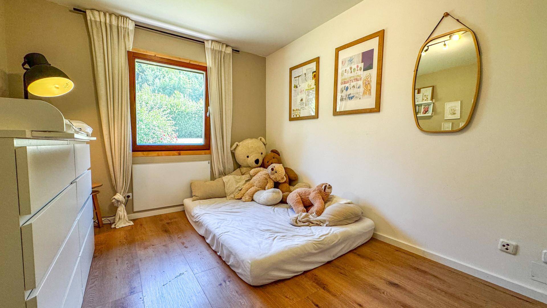 Helles Kinderzimmer mit Holzboden, Fenster und einem gemütlichen Bodenbett.