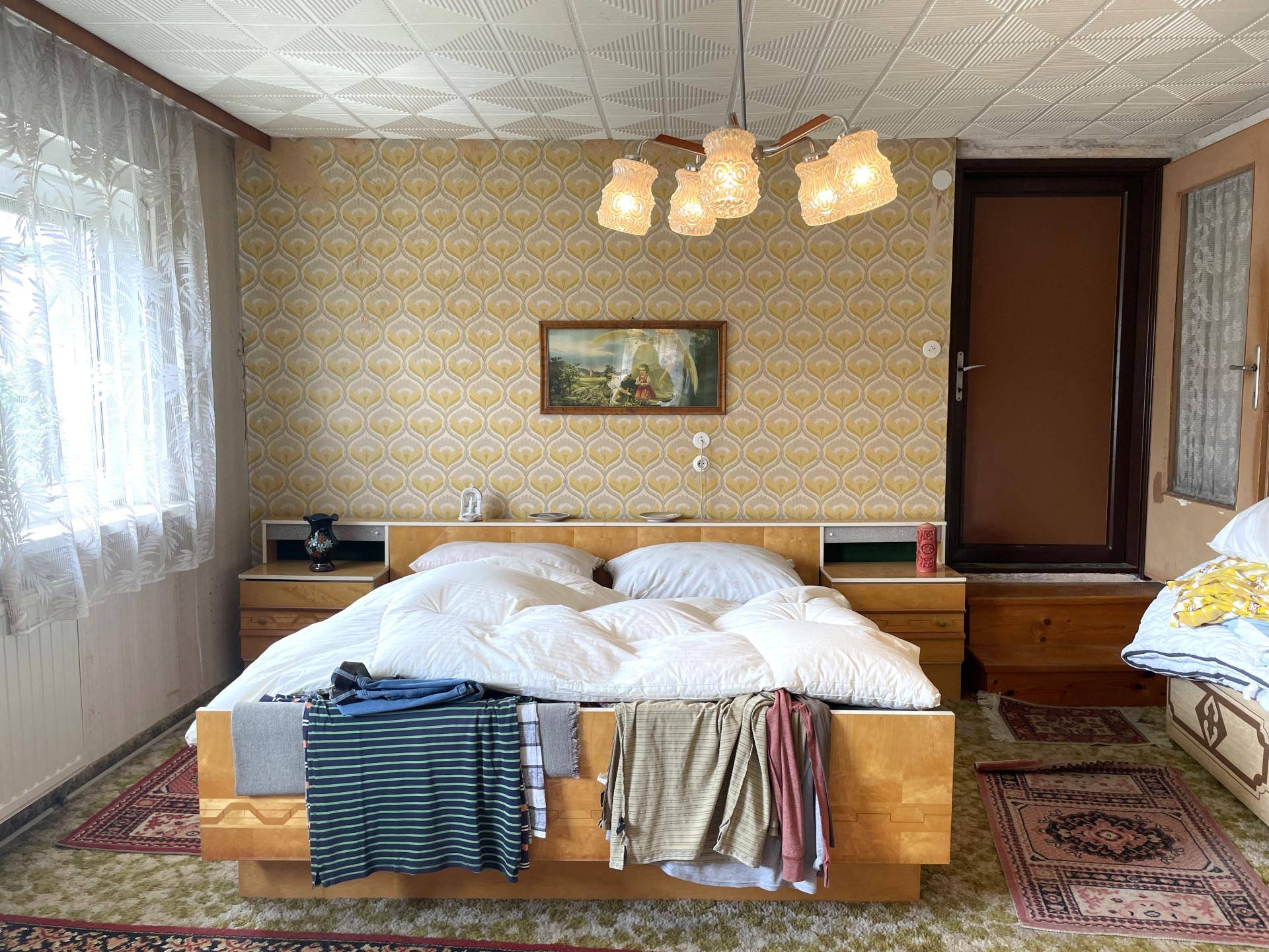 Schlafzimmer im Vintage-Stil mit gemusterter Tapete, Doppelbett und Deckenleuchte.