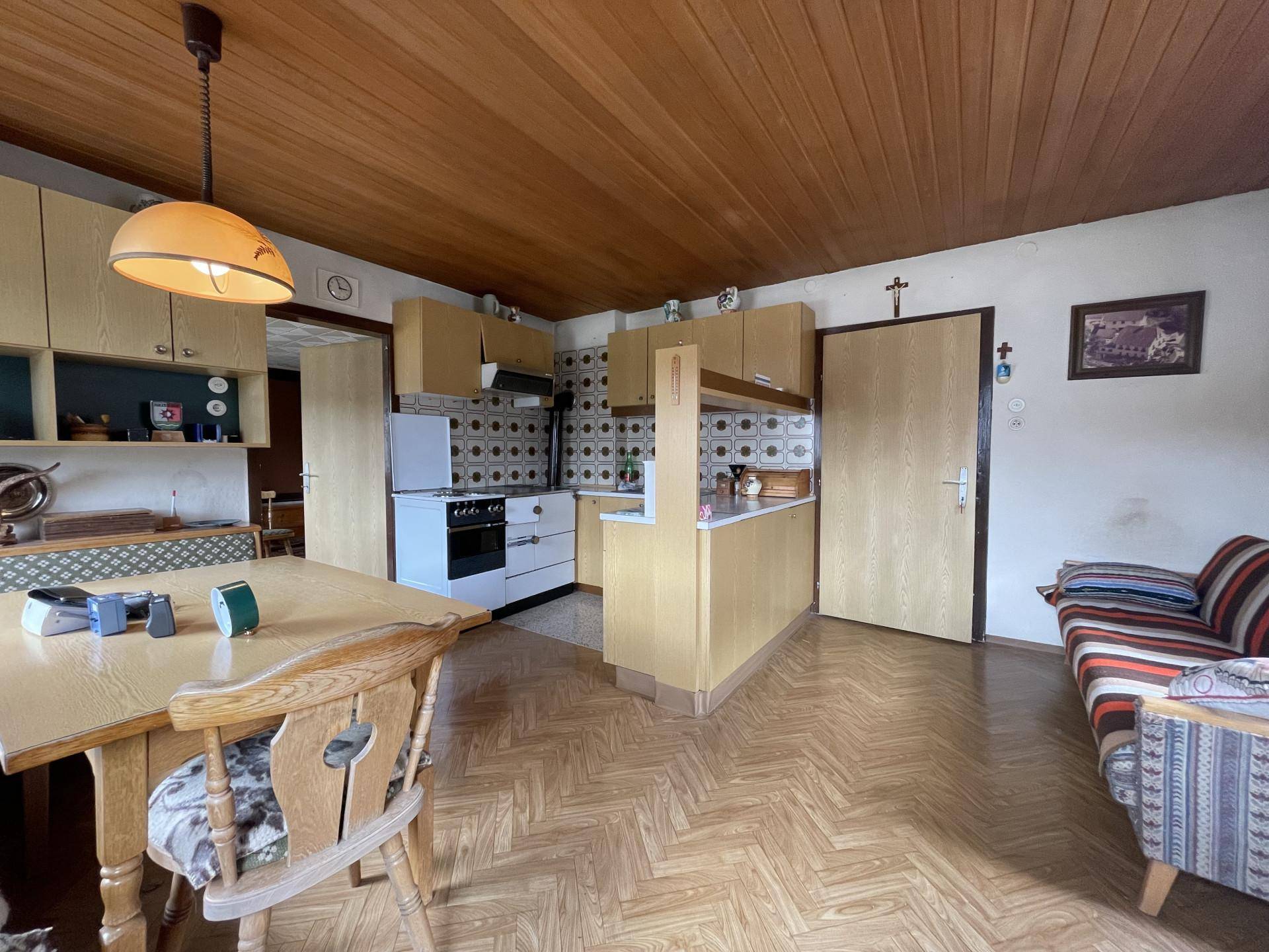 Traditionelle Küche mit Holzdecke, Esstisch und älteren Einbauschränken im Landhausstil.
