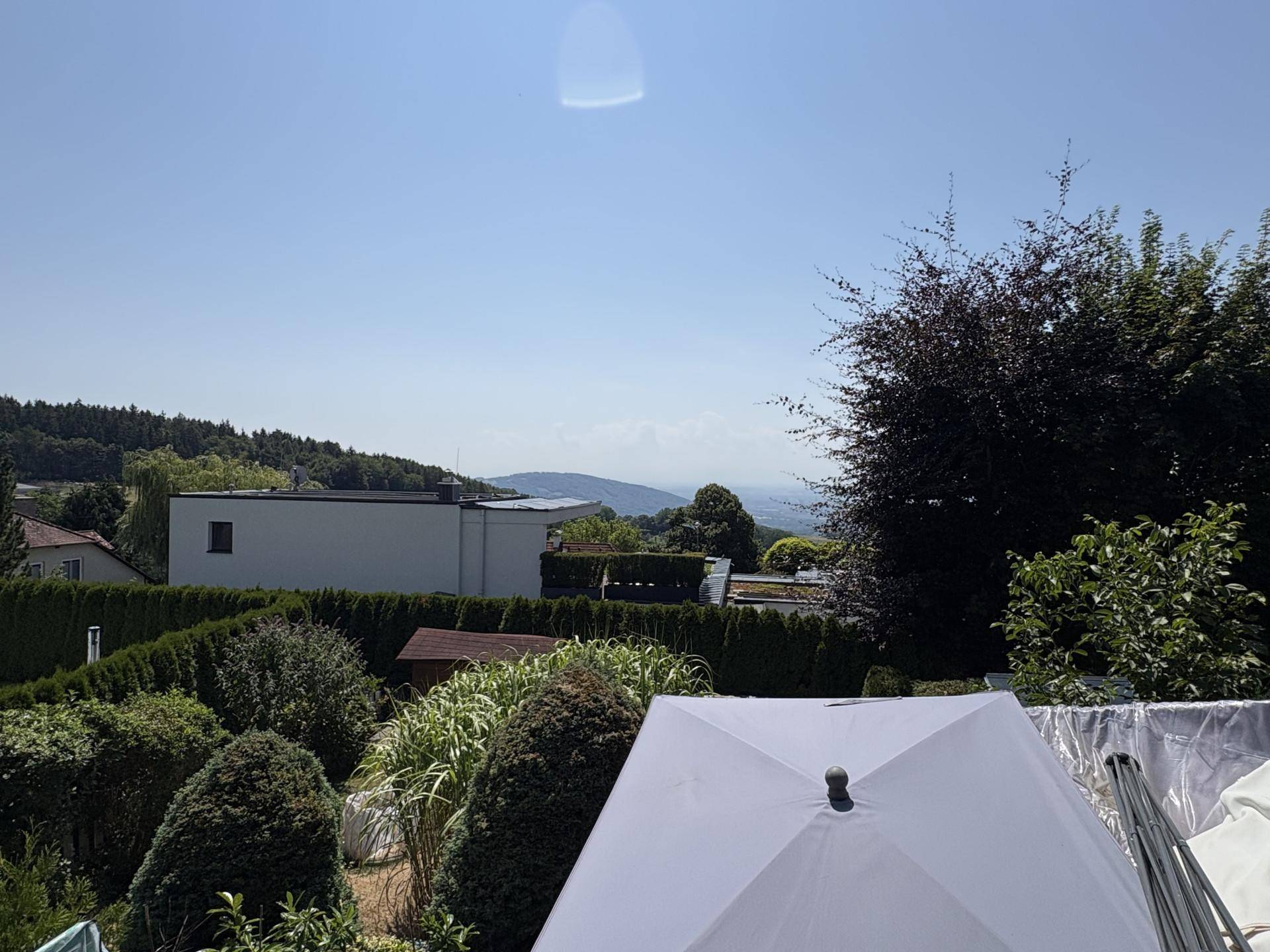 Weitläufiger Blick über die grüne Landschaft mit fernen Hügeln und Häusern.