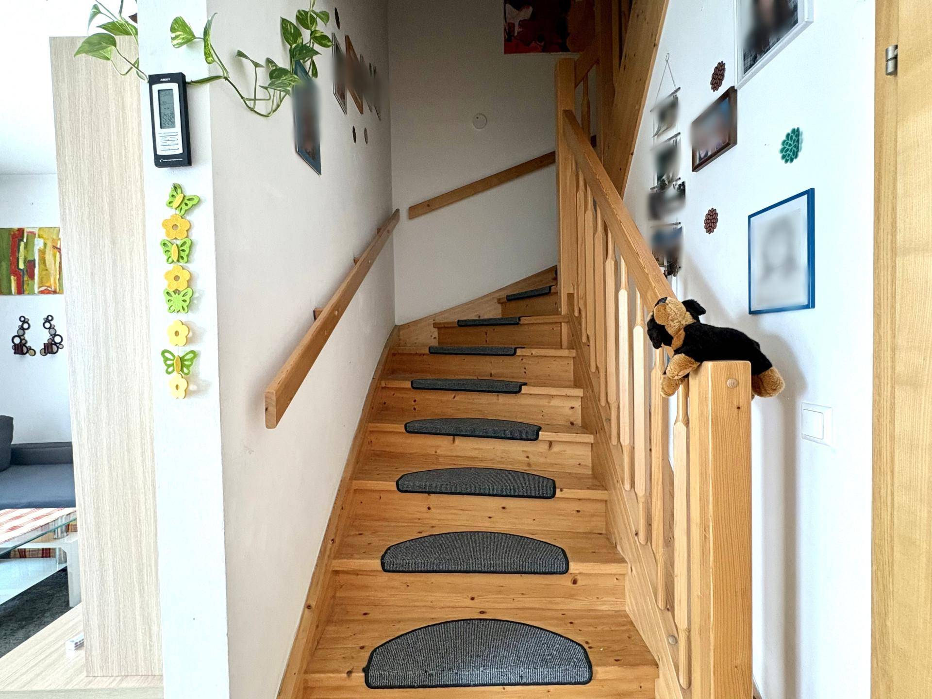 Helle Holztreppe mit Geländer führt in die oberen Stockwerke des Hauses.