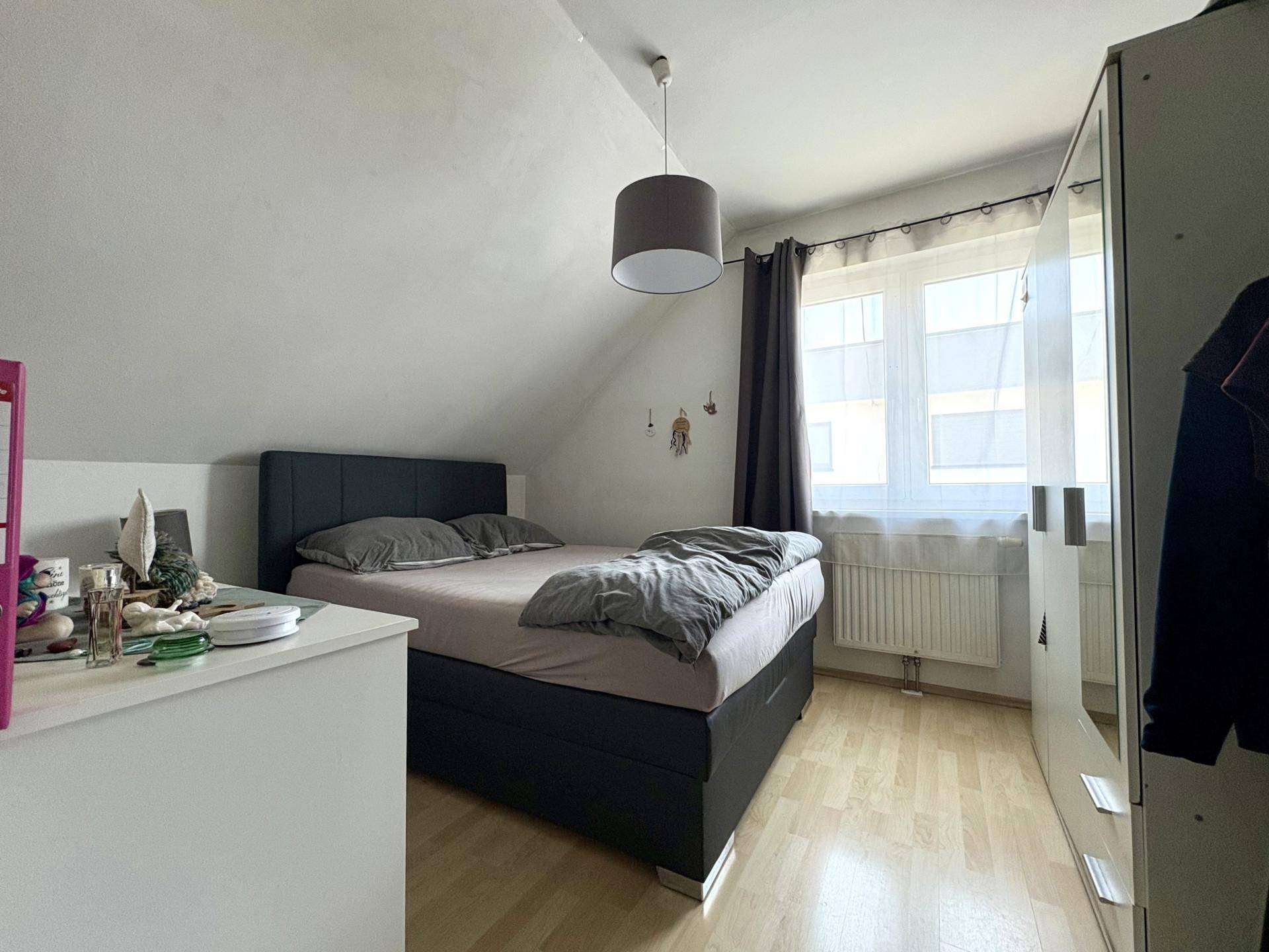 Schlafzimmer im Dachgeschoss mit Doppelbett, Kleiderschrank und schrägen Wänden.
