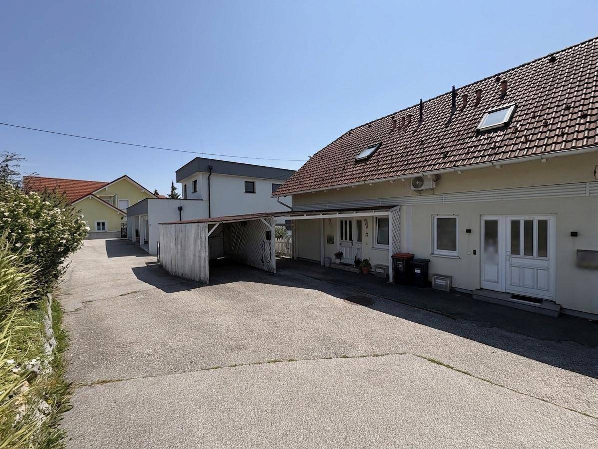 Gesamtansicht des Hauses mit Zufahrt, Carport und umliegender Bebauung.
