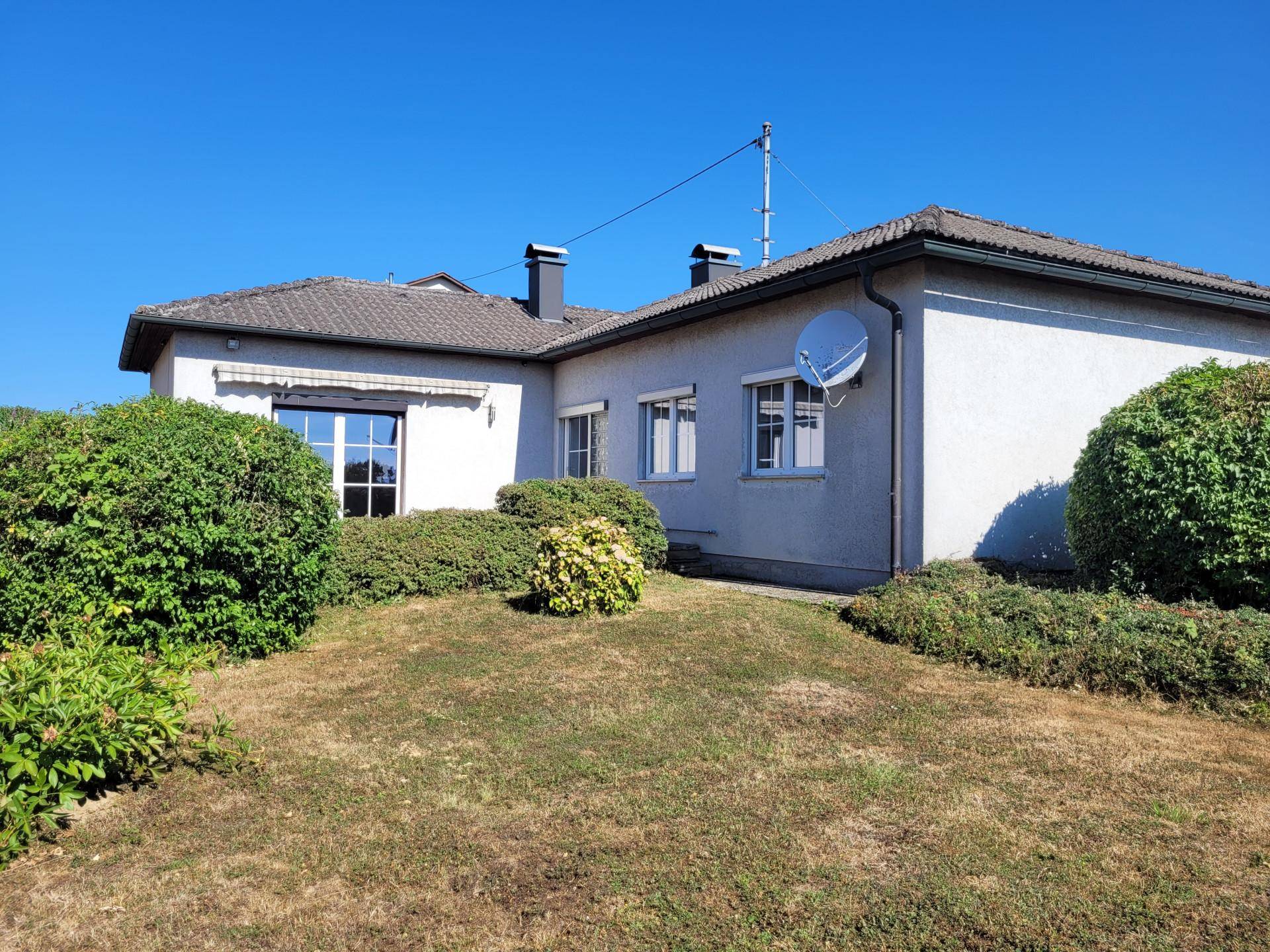 Rückansicht des Hauses mit Satellitenschüssel und gepflegter Gartenanlage bei Sonnenschein.