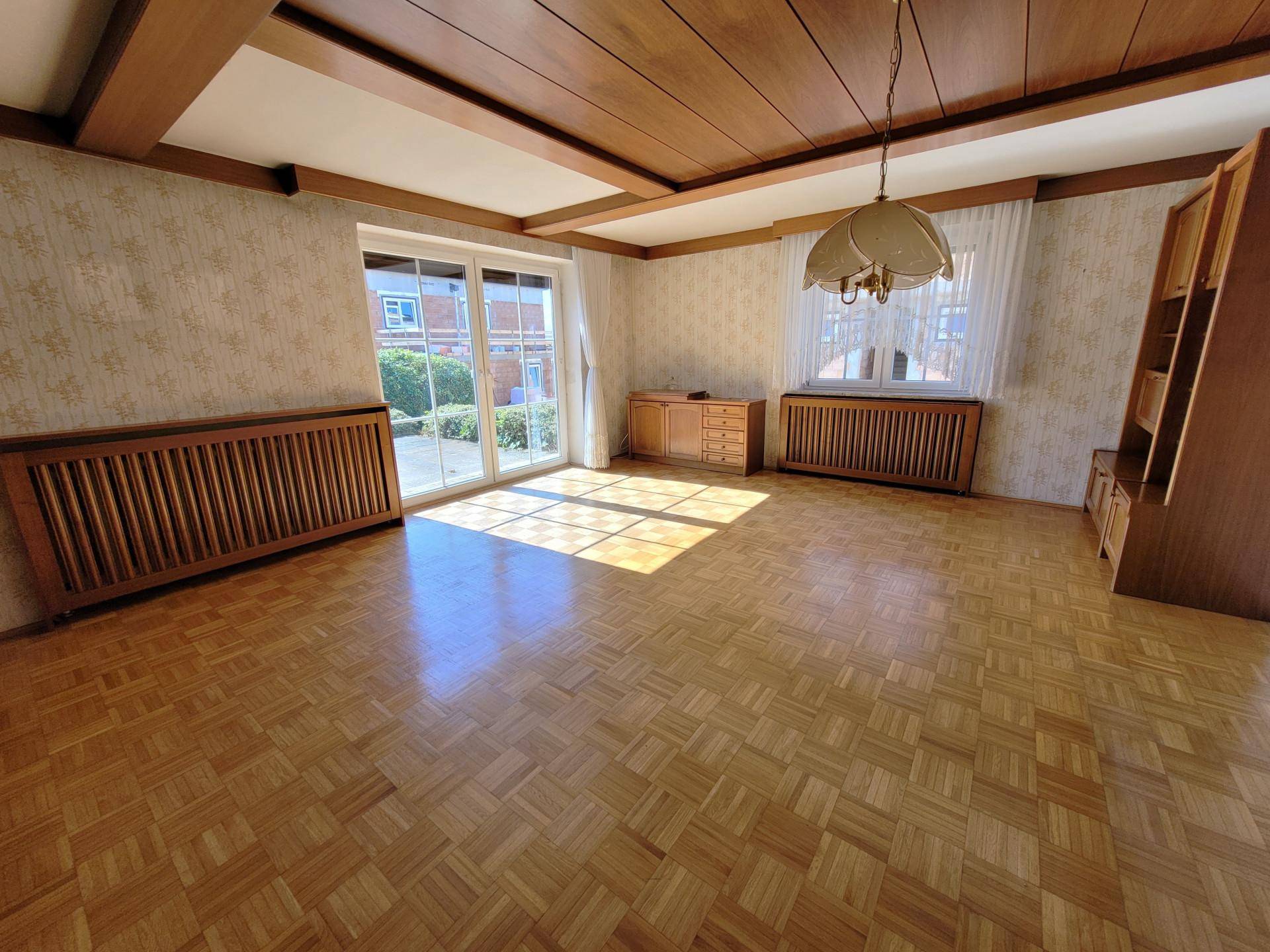 Helles Wohnzimmer mit Parkettboden, Holzdecke und Zugang zur Terrasse.