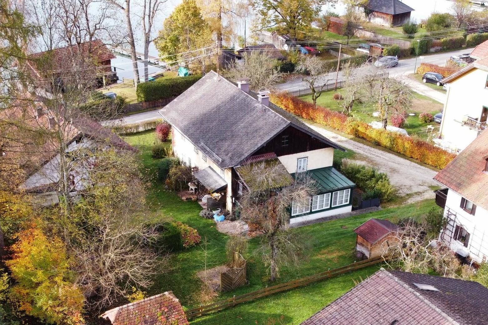 Luftaufnahme des Anwesens mit Haus, großem Garten und der umliegenden Landschaft am See.
