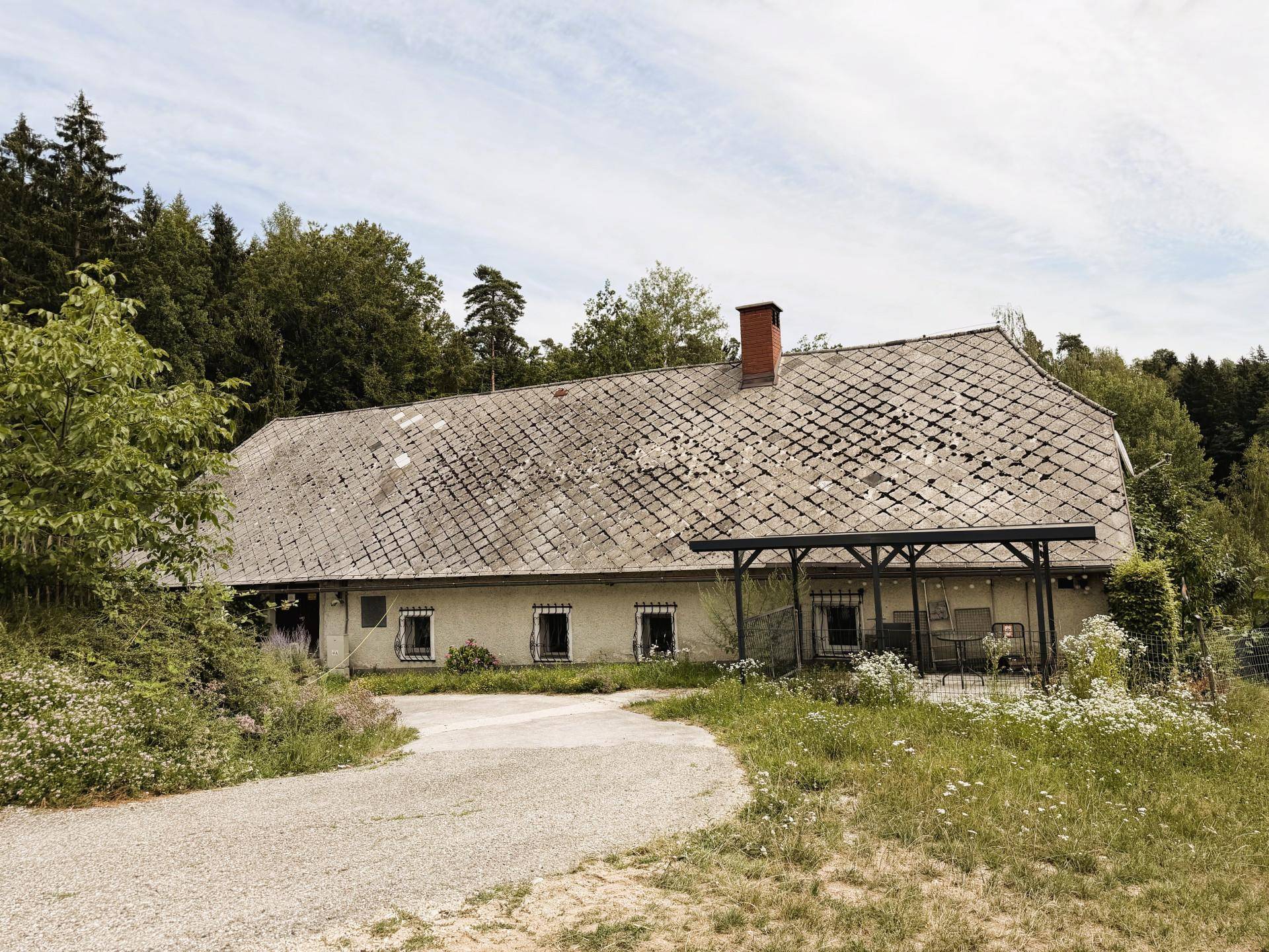 Ländliches Gebäude mit traditionellem Dach und überdachtem Sitzbereich im Freien.